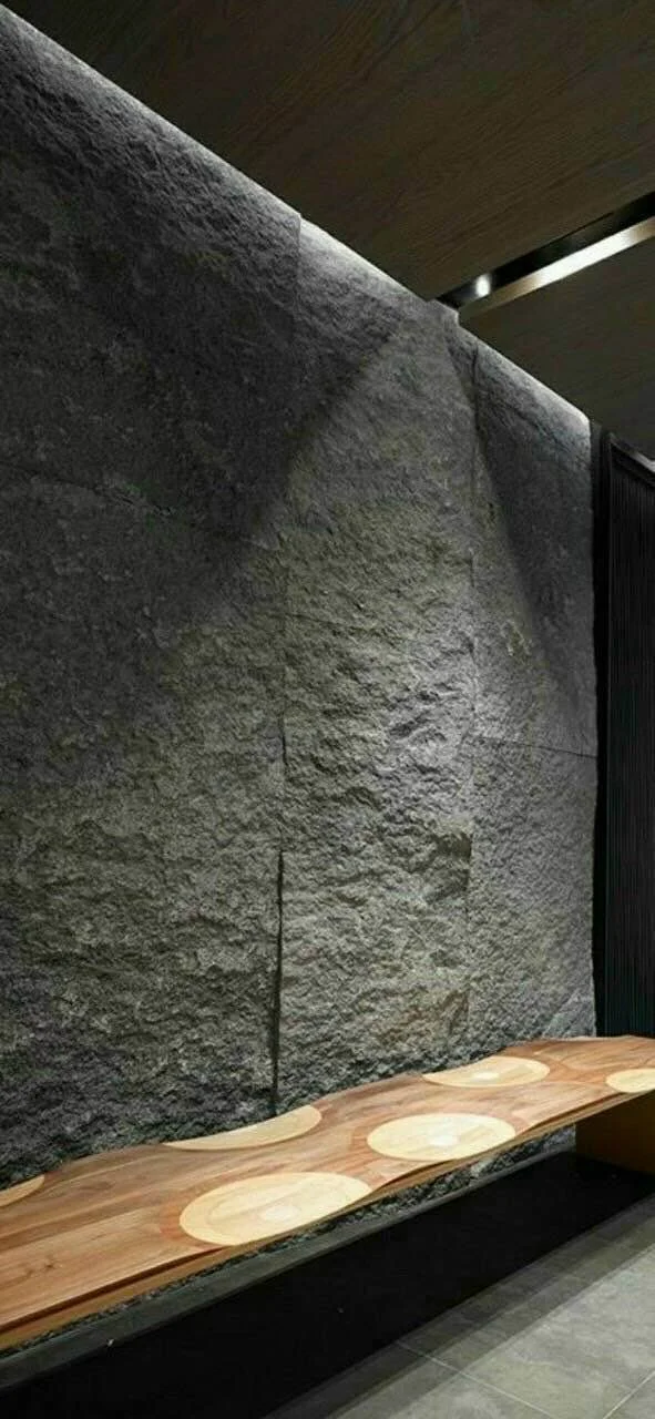 Textured stone wall with wooden bench in modern interior