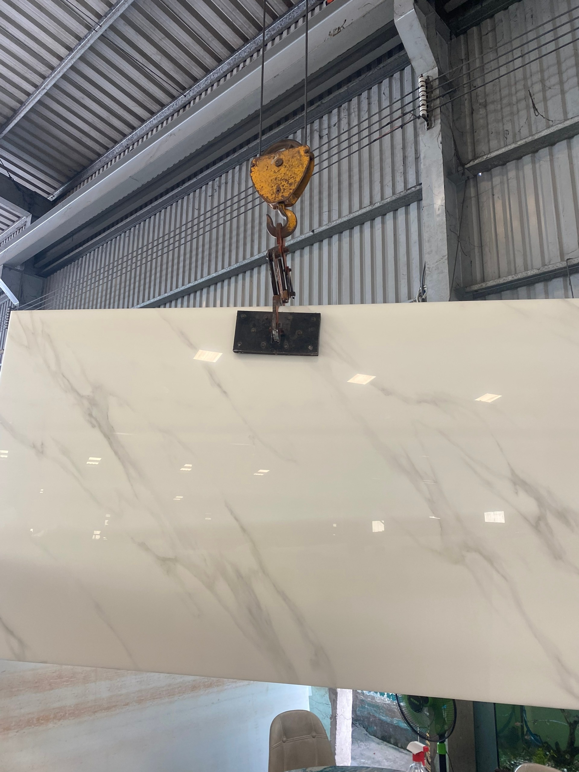 Marble slab being lifted by a crane in a warehouse