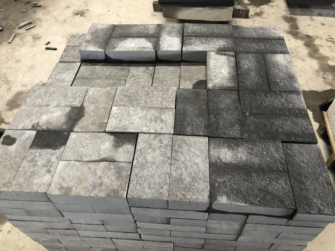 Stack of gray rectangular stone tiles arranged in a spiral pattern on the ground.