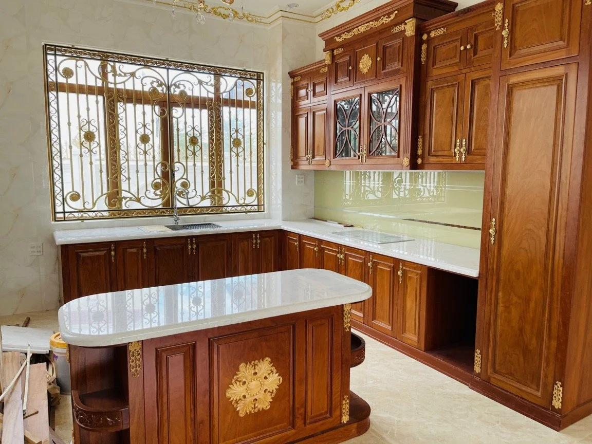 Luxurious kitchen with ornate wooden cabinetry, marble countertops, and decorative metal window grills.