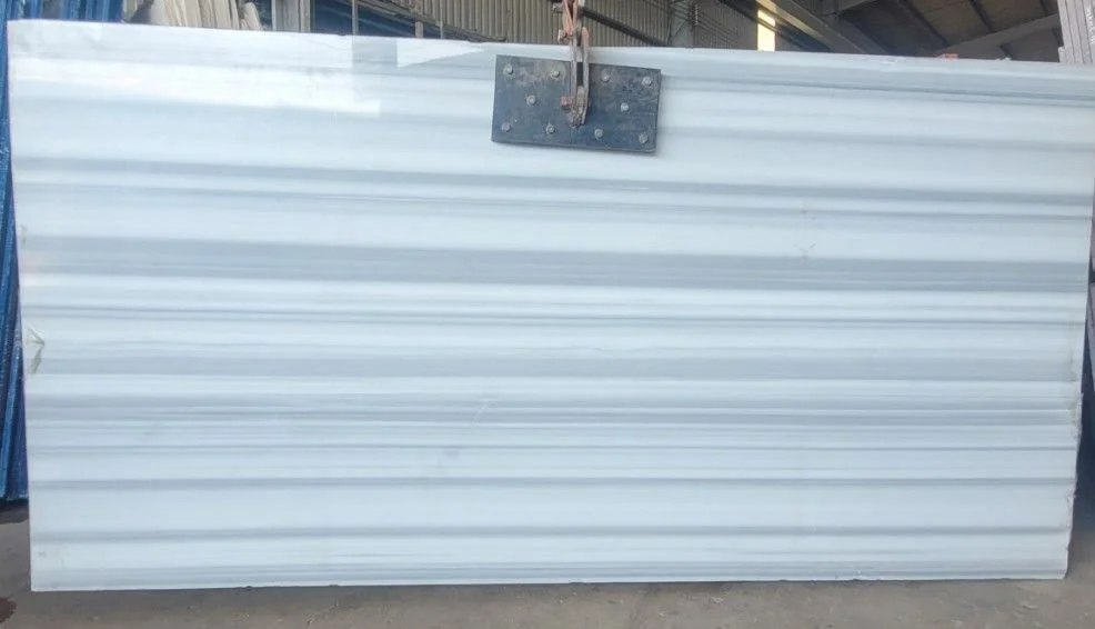 Large white marble slab with gray horizontal stripes, suspended by a metal clamp in an industrial setting.