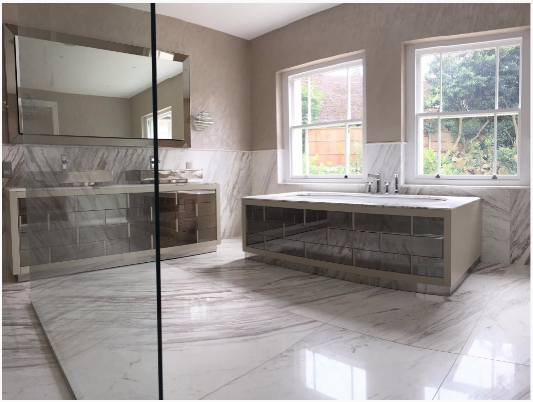 modern bathroom with marble tiles, large mirrors, glass shower, and windows