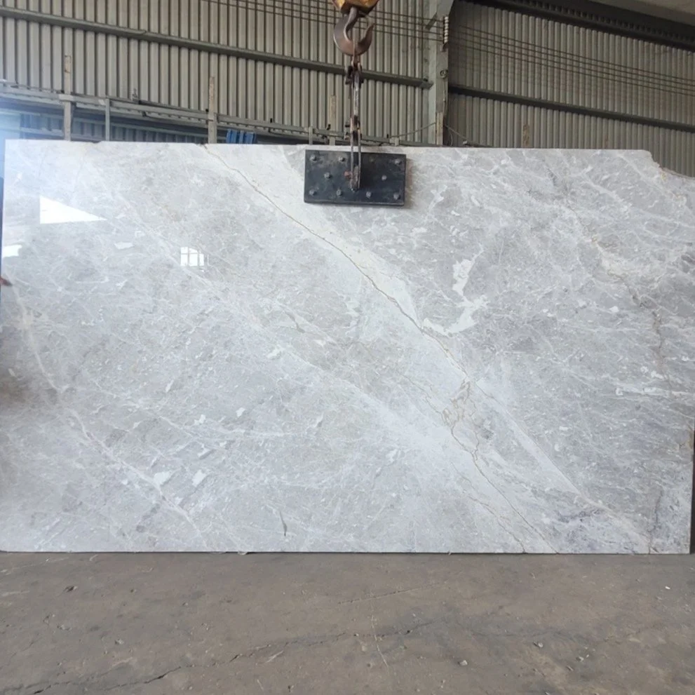 Large gray marble slab in a warehouse with lifting equipment attached.