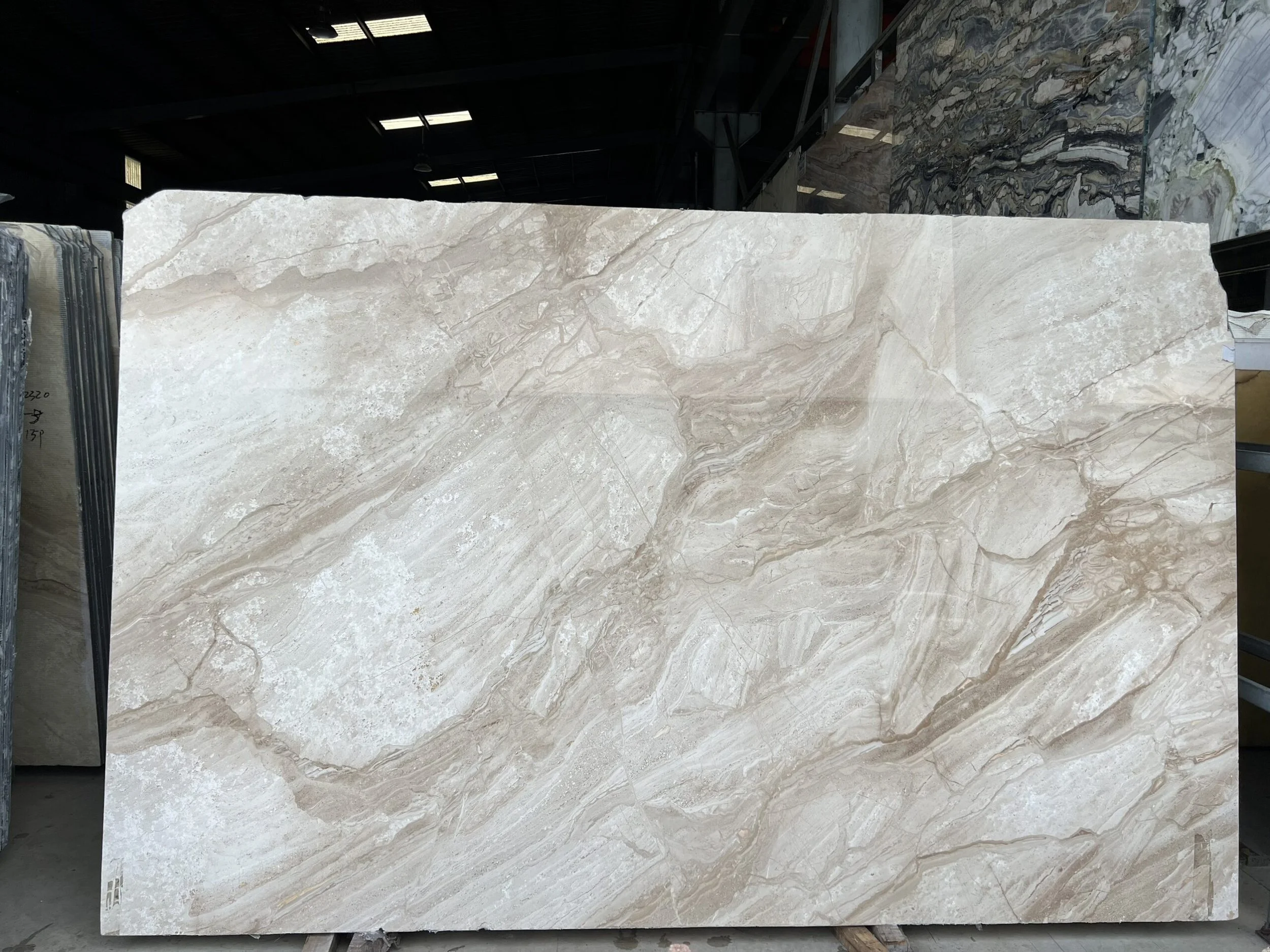 Large marble slab with beige and white veining in warehouse