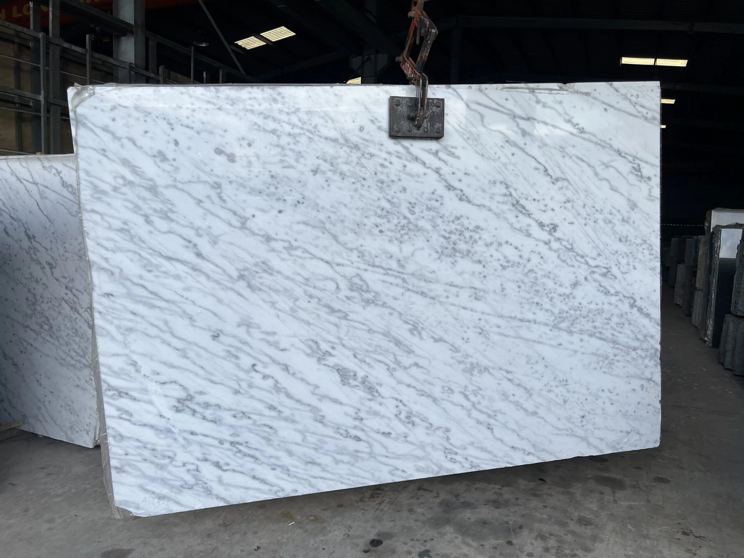 large marble slab with gray veining in a warehouse setting