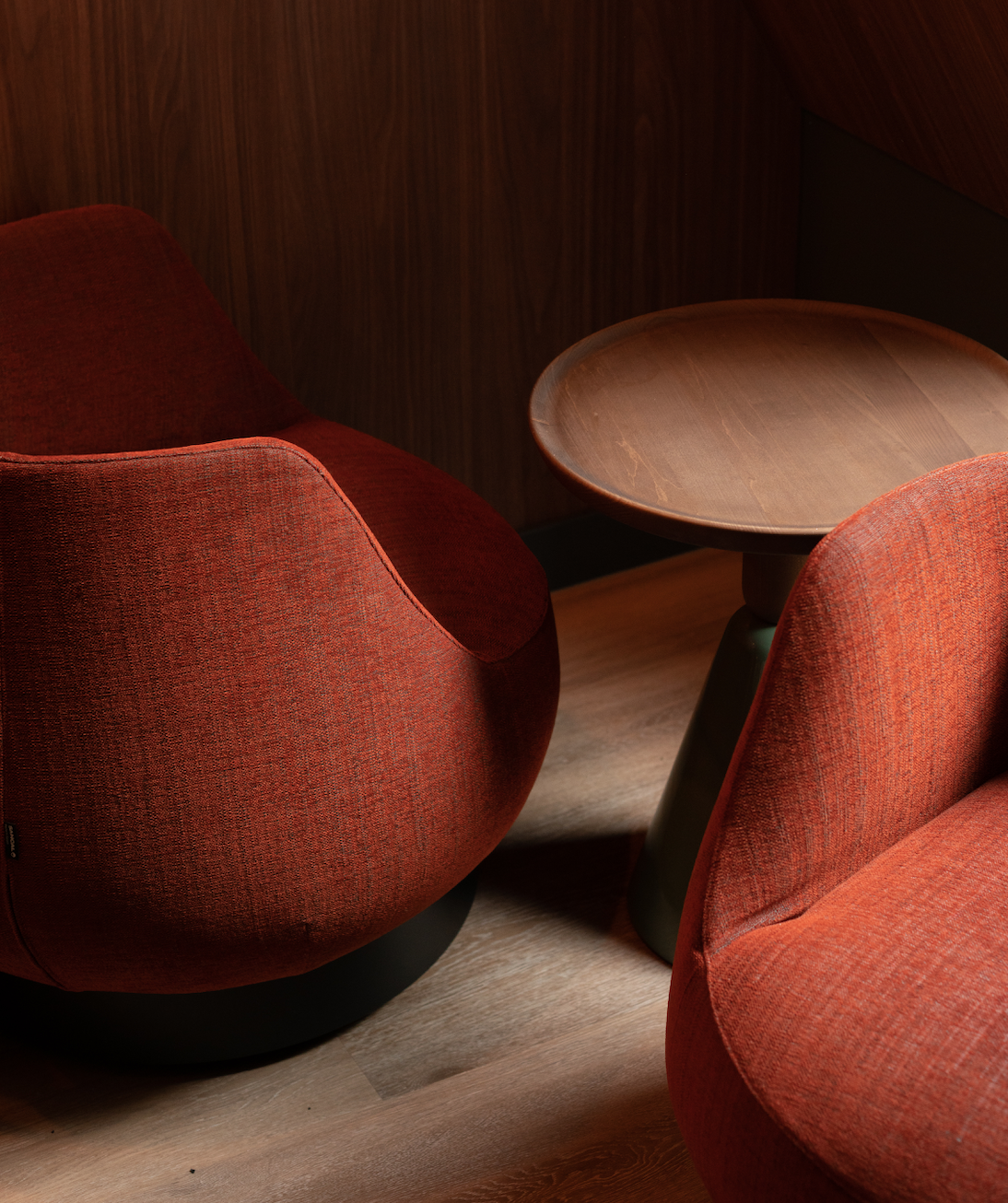 Two red upholstered chairs and a round wooden table in a cozy corner.