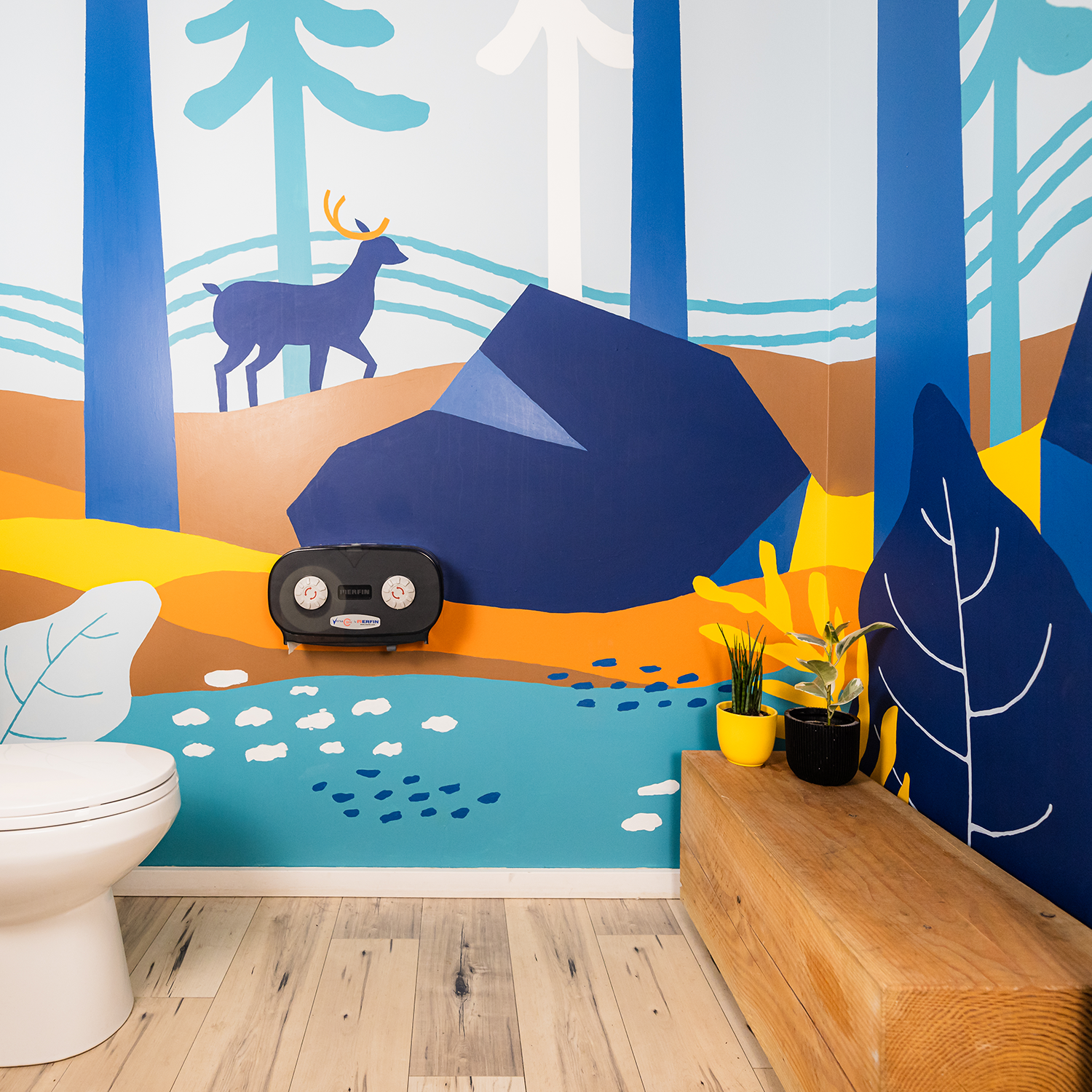 Colourful mural in a bathroom depicting a forest scene with boulders, a deer, trees, and a river running through.
