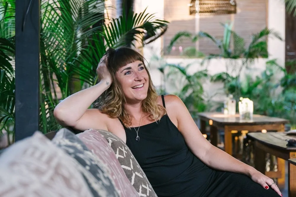Dr Stephanie Minchin relaxing on a sofa surrounded by tropical plants