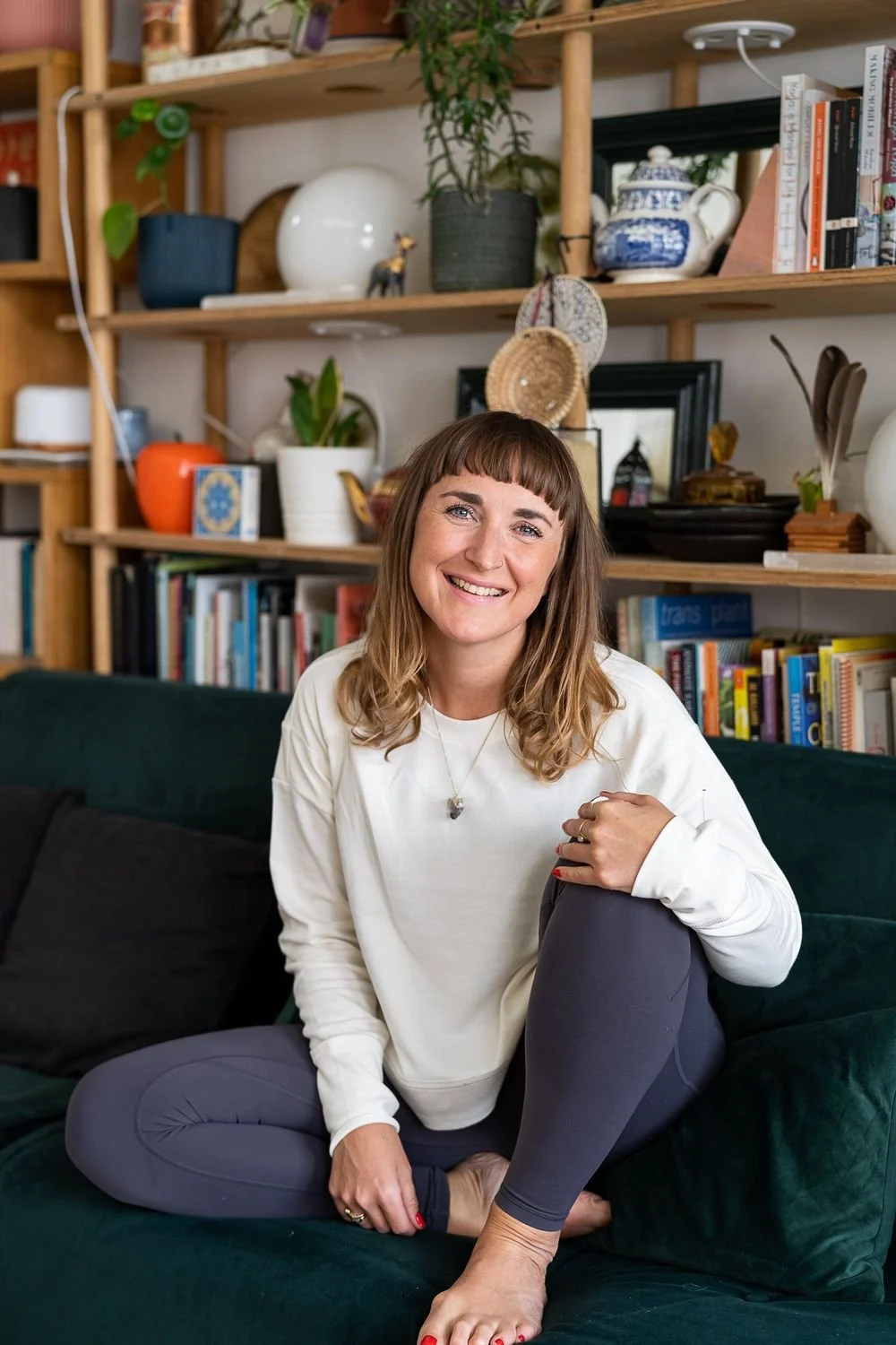 Dr Stephanie Minchin seated on a green sofa in front of a bookshelf