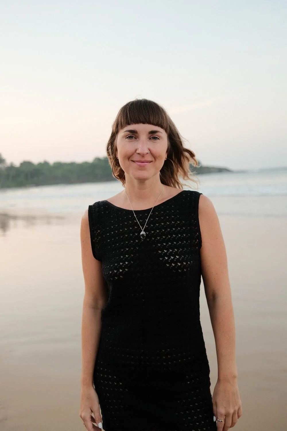 Dr Stephanie Minchin standing by the water at sunrise