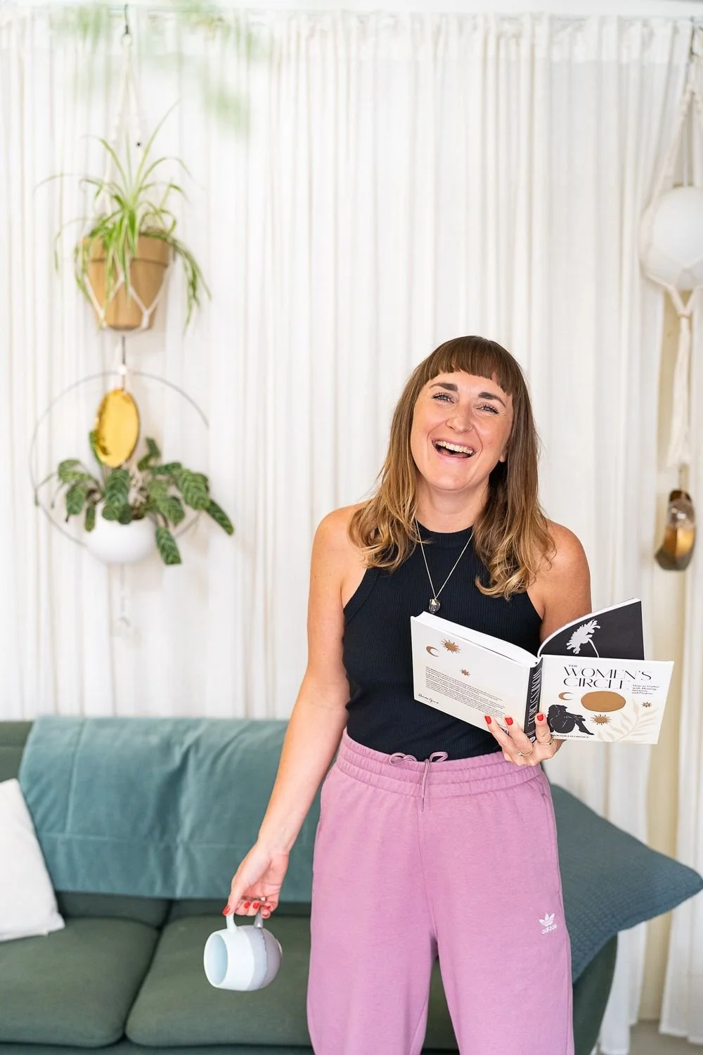 Dr Stephanie Minchin holding a book and a cup of tea in a bright studio