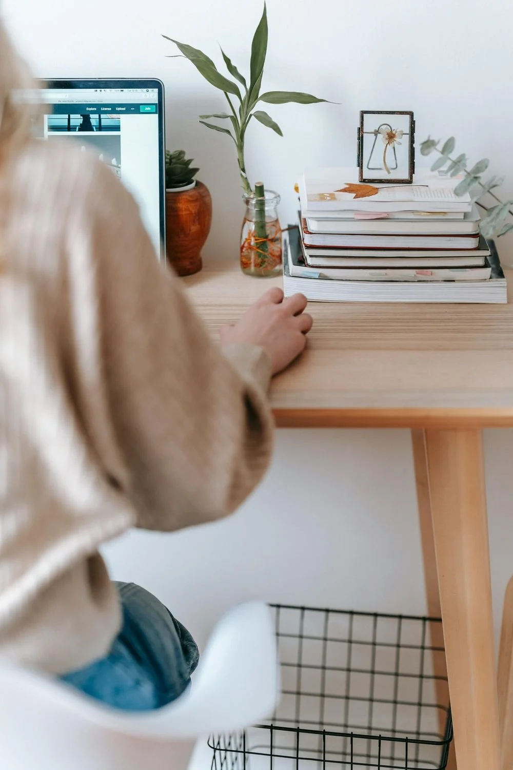 Person working at a laptop at a tidy desk with plants