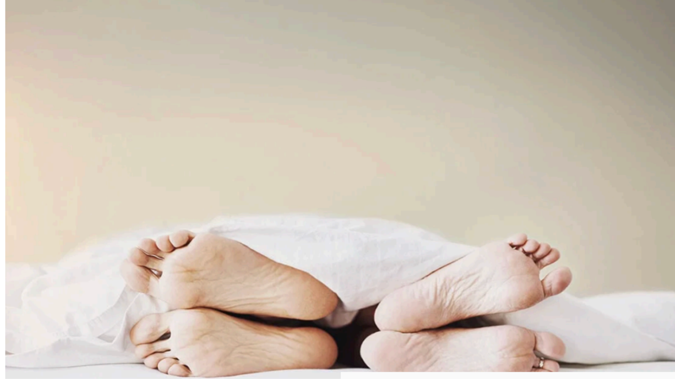 couple lying away from each other in bed with white sheets