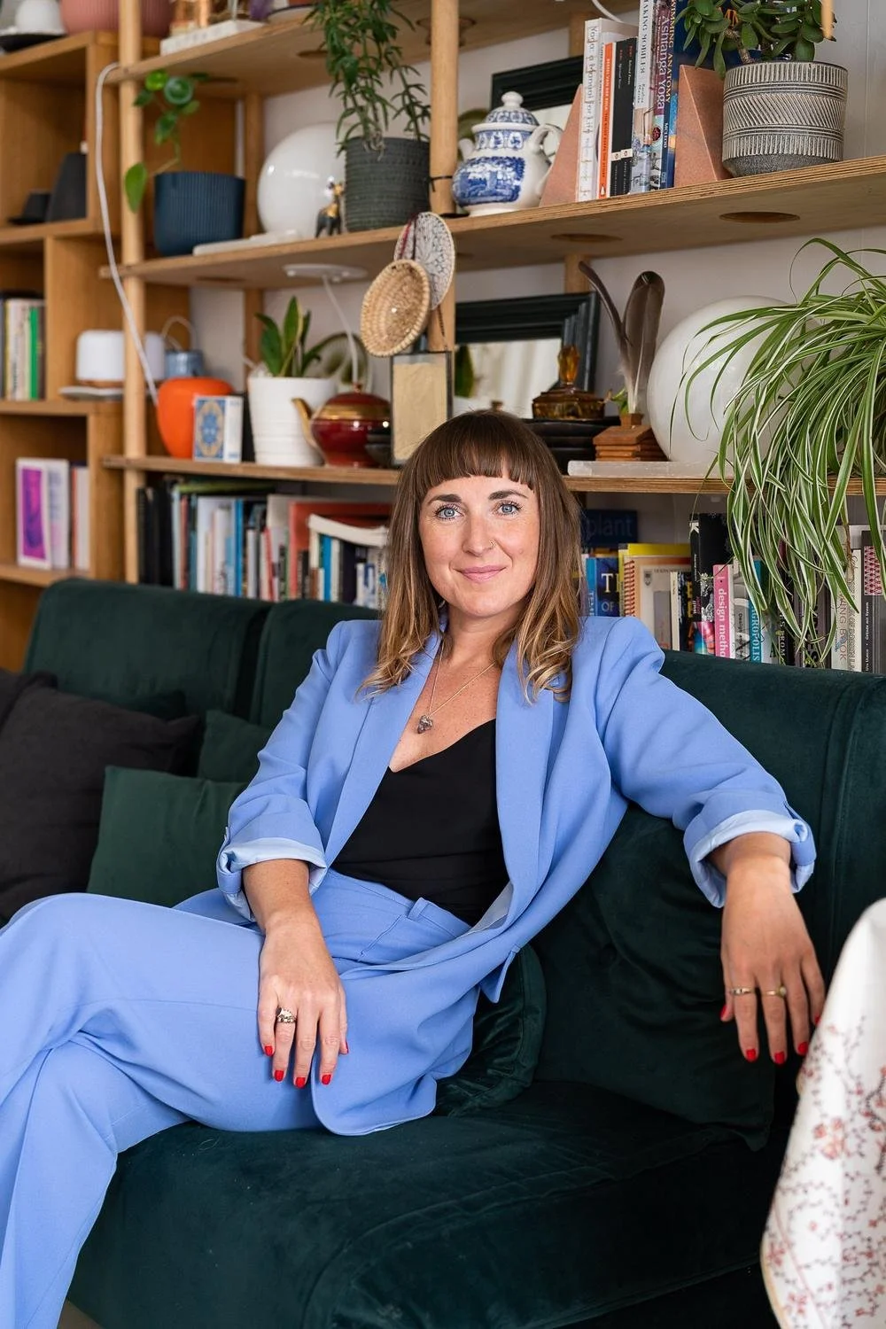 Dr Stephanie Minchin in a blue suit, seated on a green velvet sofa