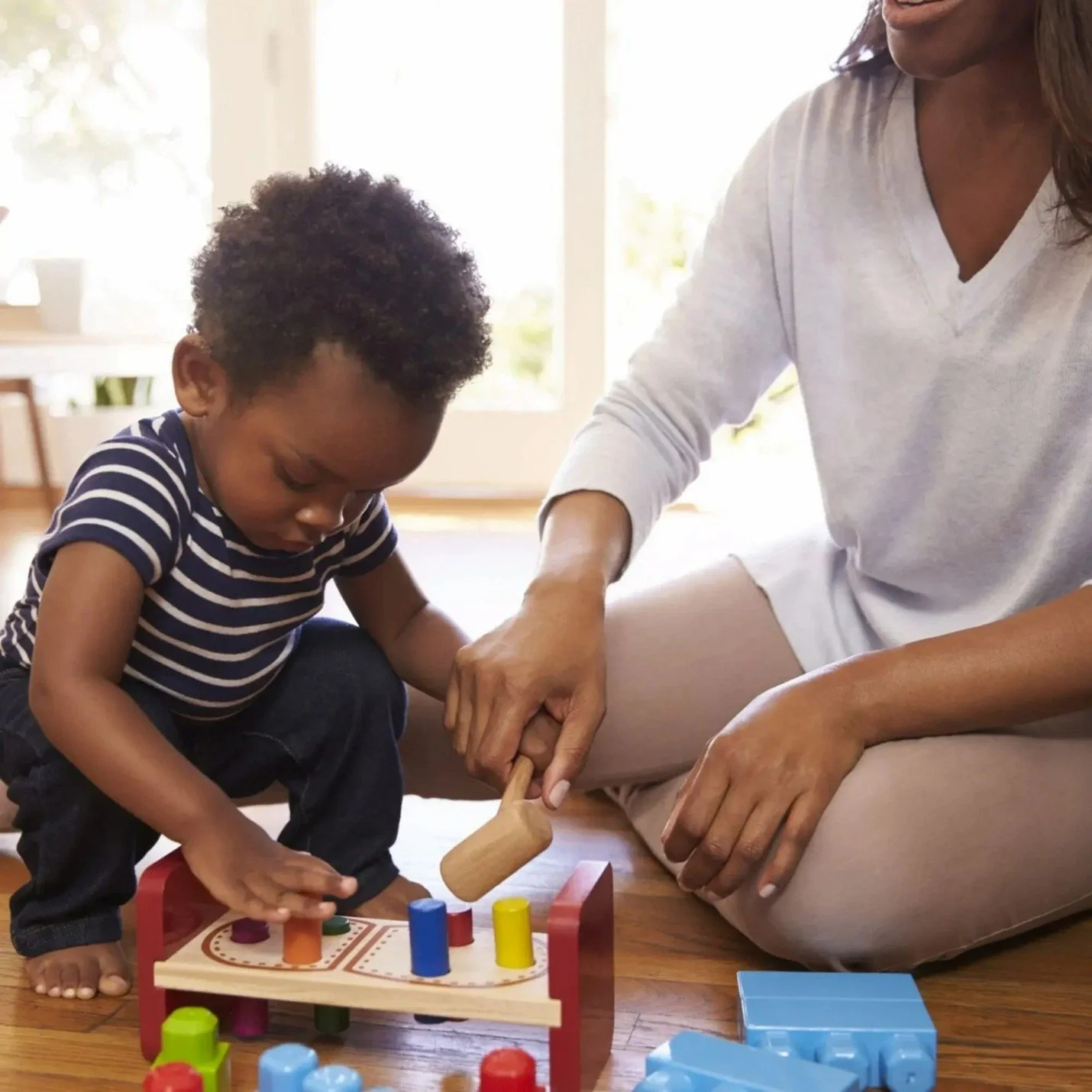 Speech therapist providing play-based therapy to a toddler in a home environment
