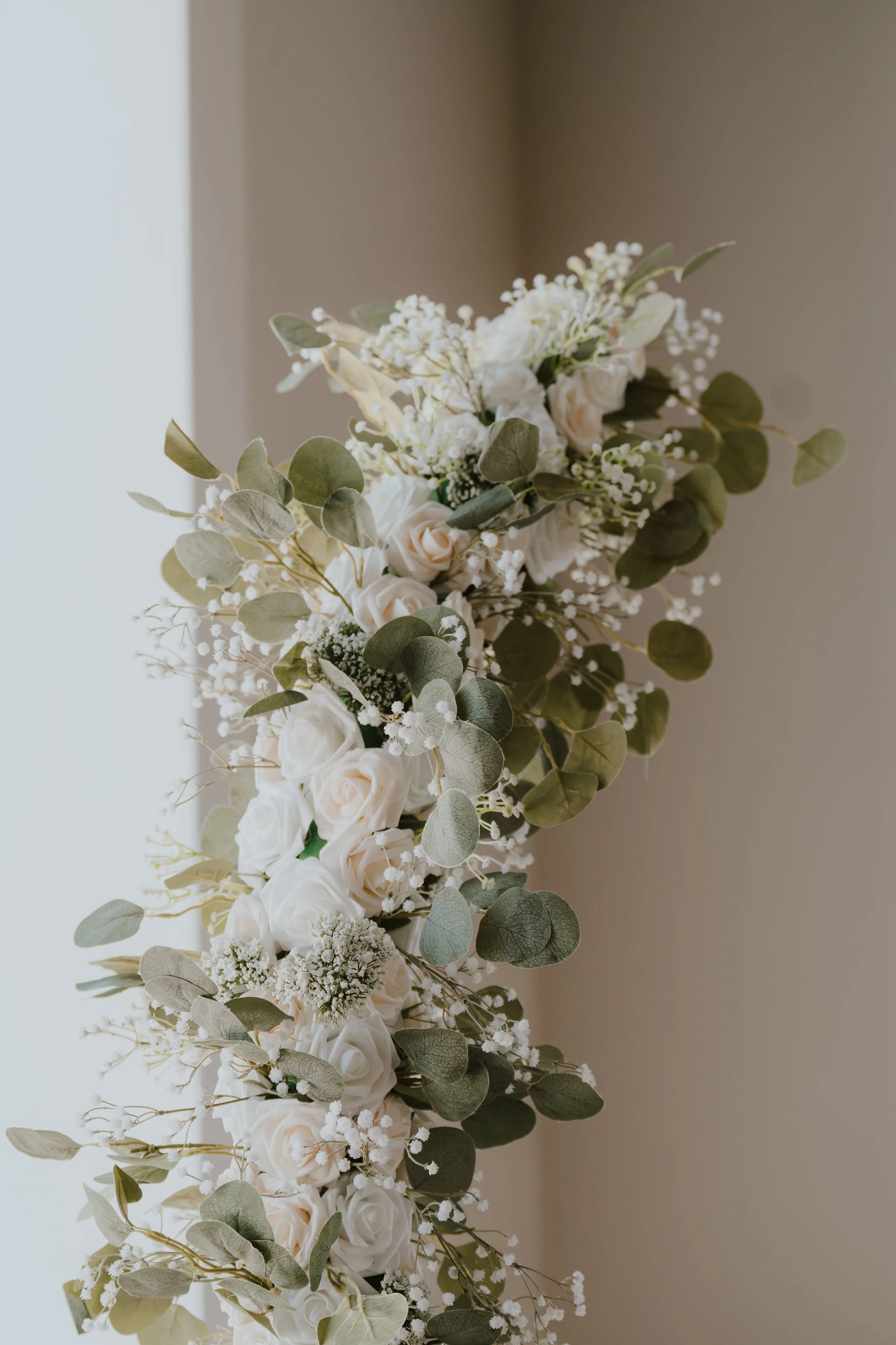 Elegant floral arrangement with white roses, baby's breath, and eucalyptus leaves.