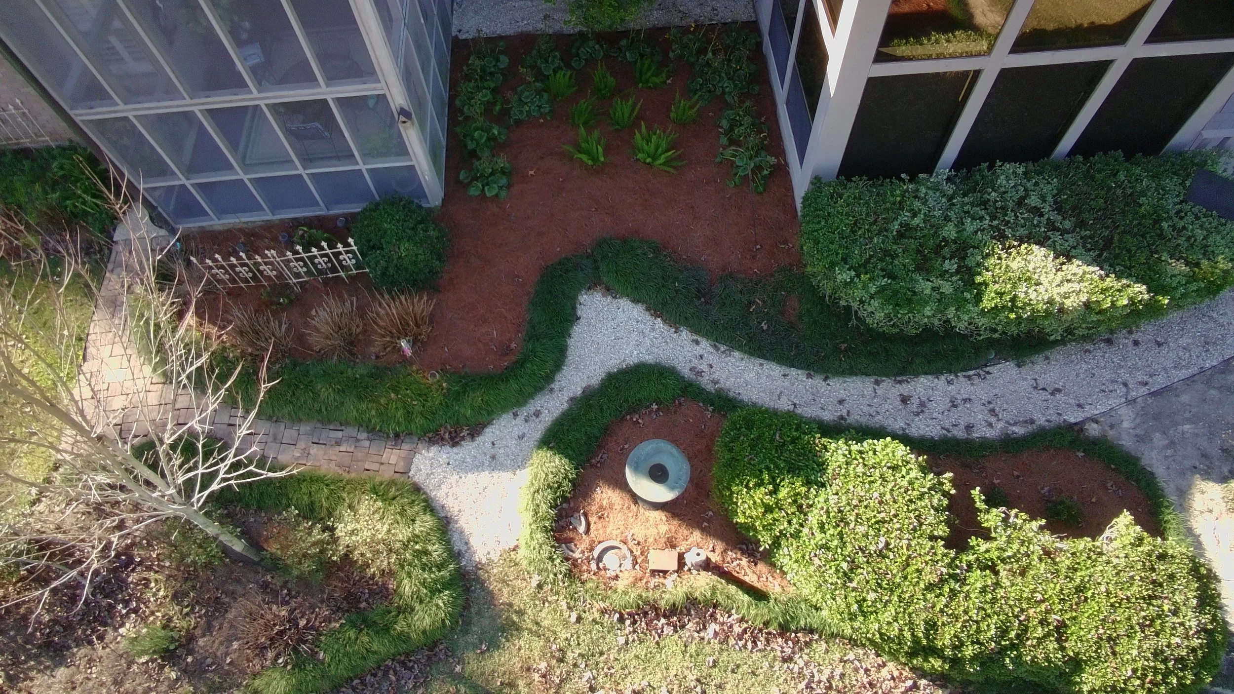 drone picture looking down on a rocky backyard path with landscaping around it