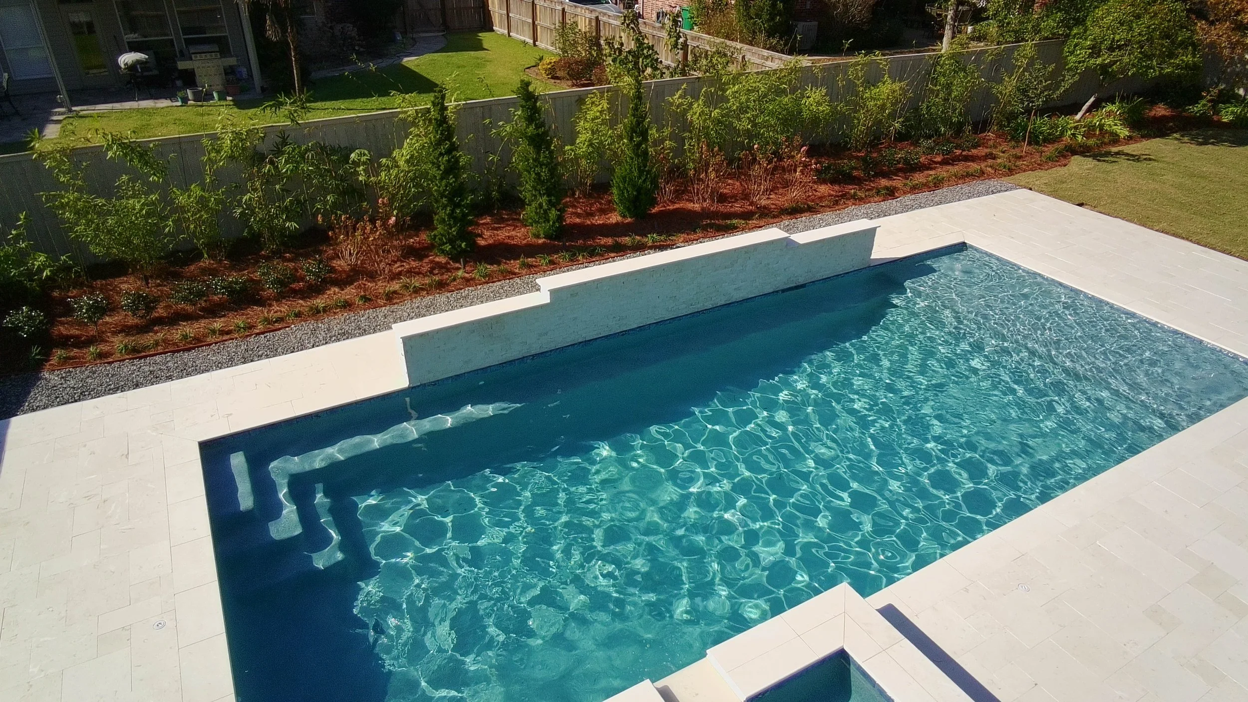 image of three rows of plants lining the fence behind a pool
