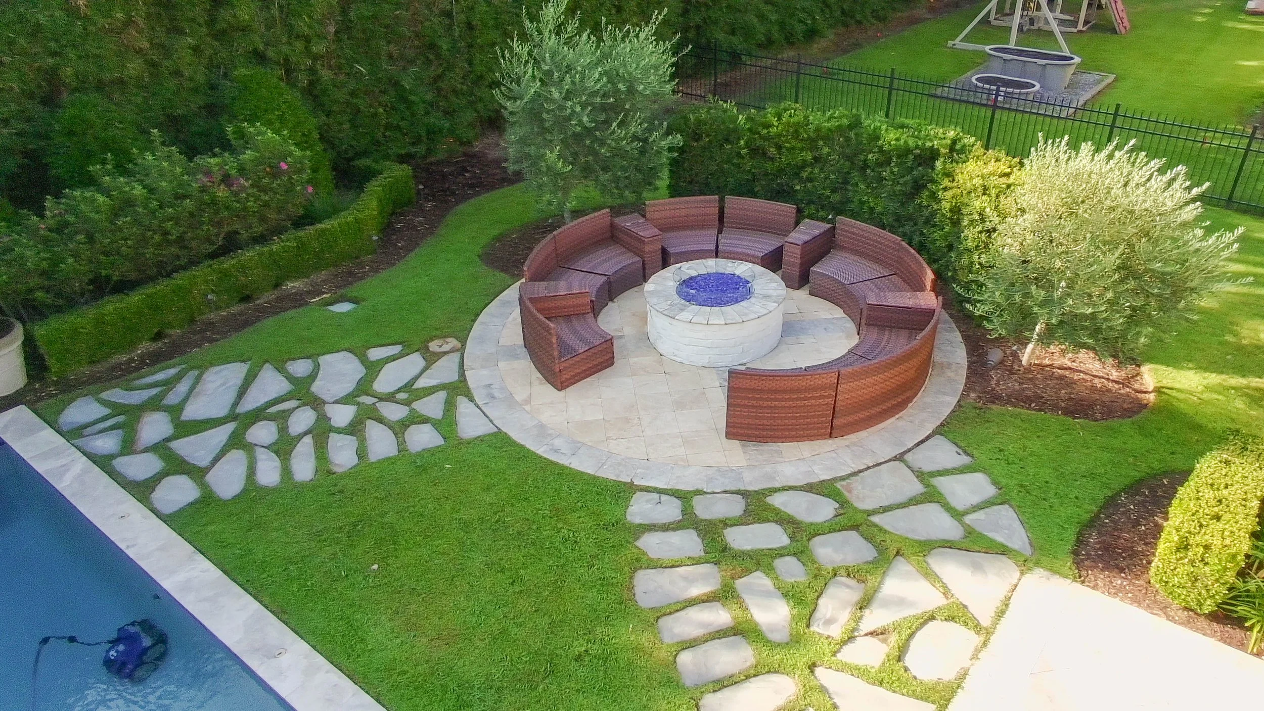 a fire pit area with a paver walkway leading to it from a pool