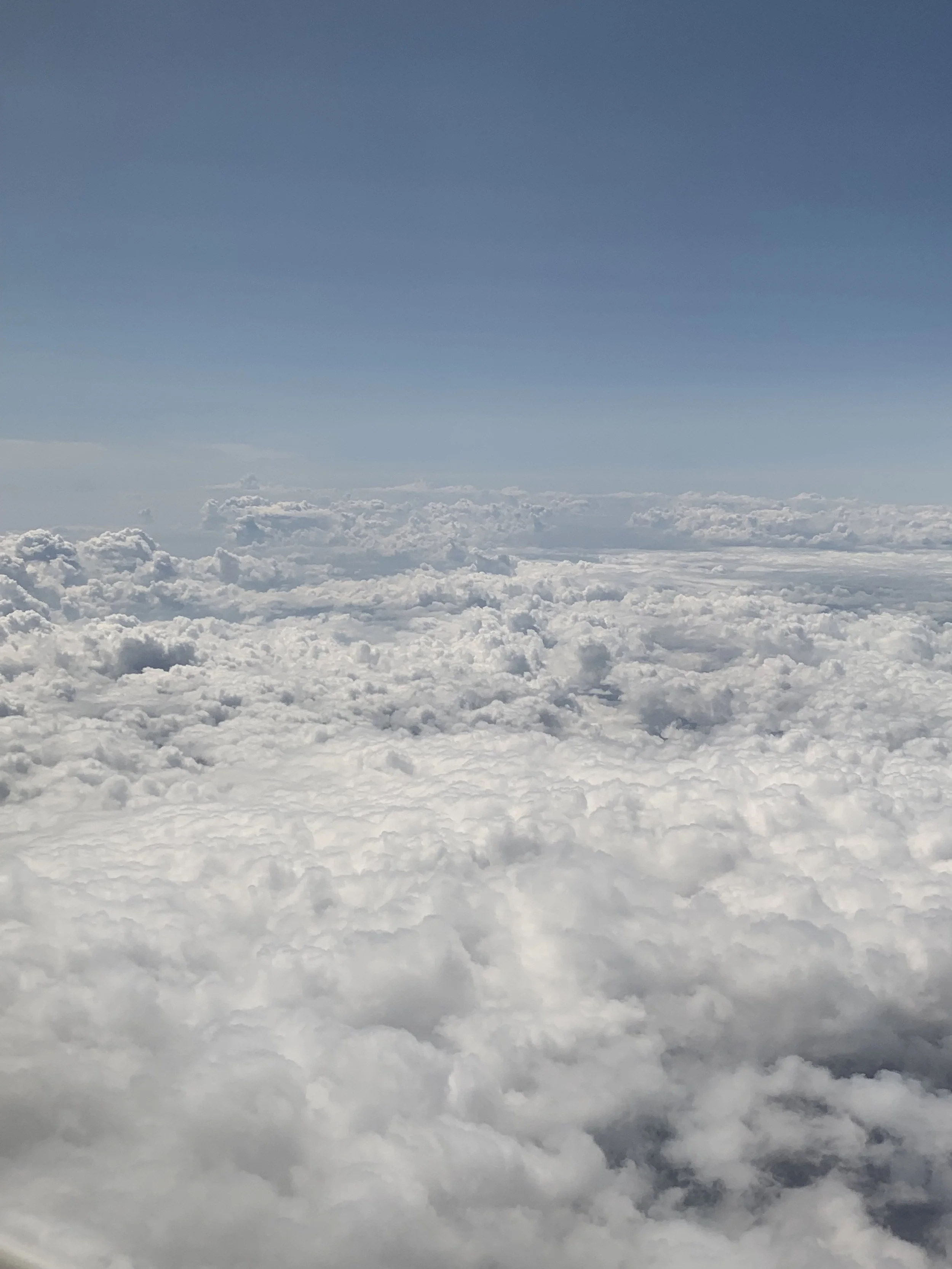 Aerial view of a cloudy sky with blue sky above.