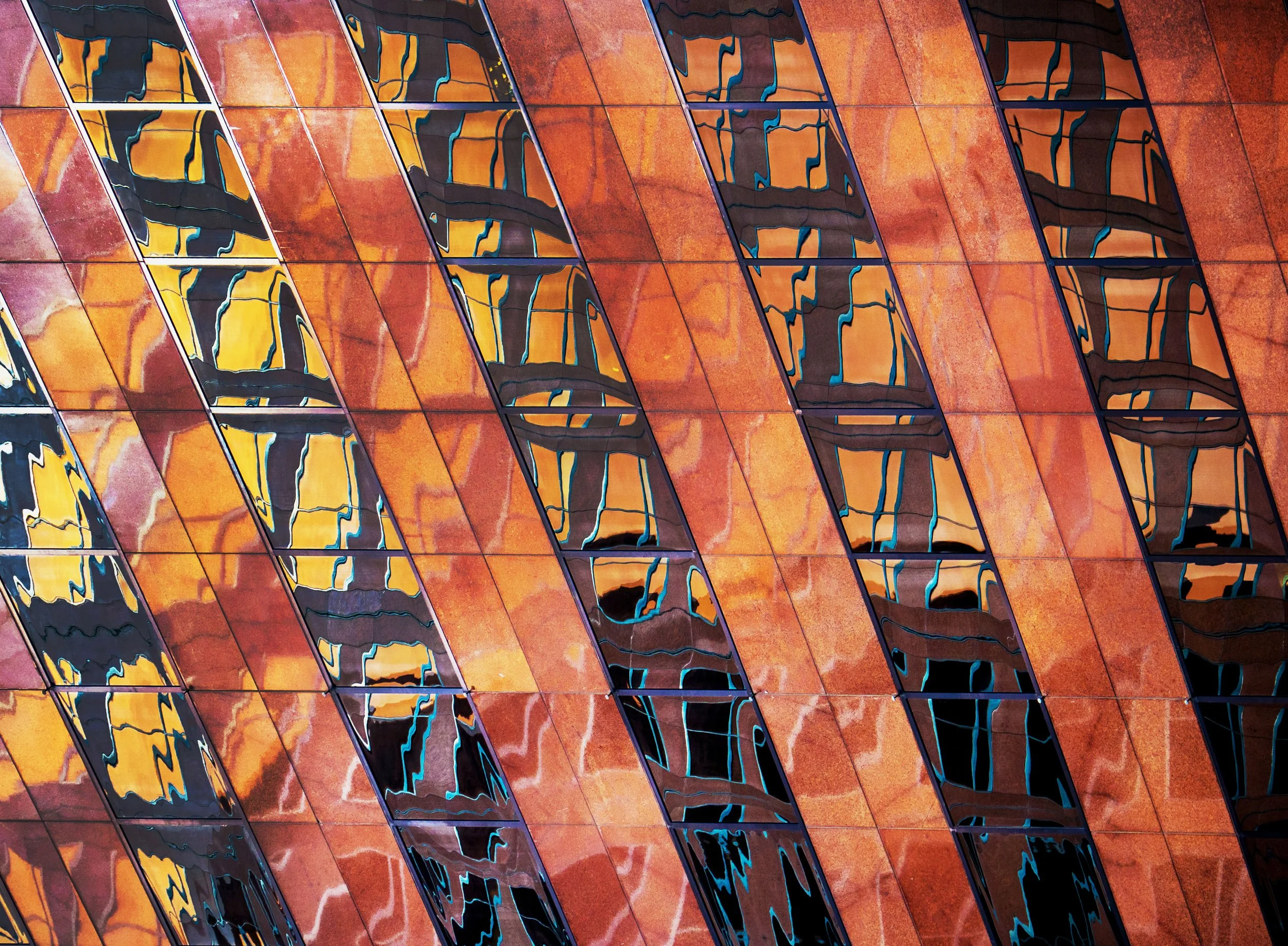 Abstract orange and brown geometric pattern with distorted dark reflective shapes and bright blue accents