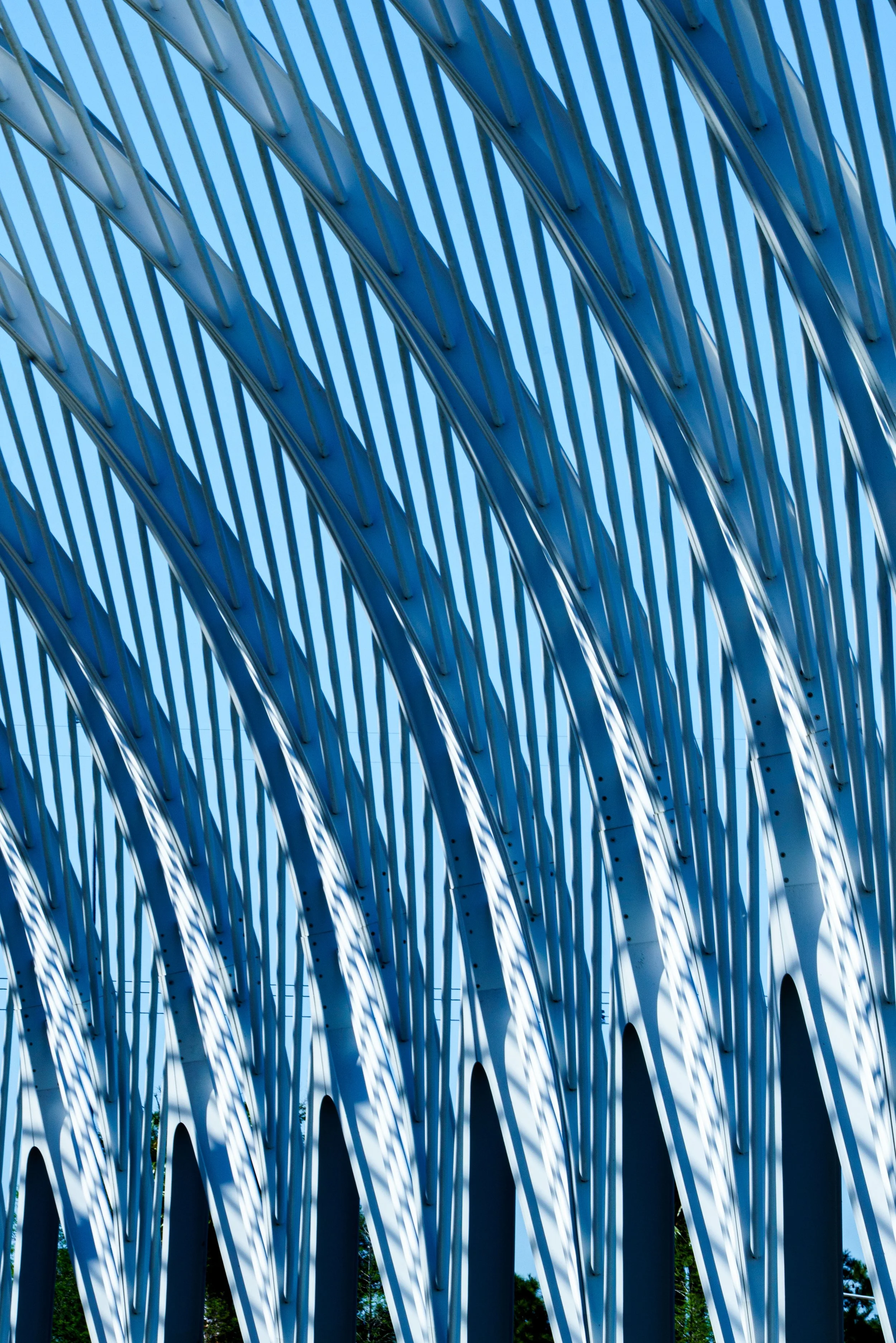 Abstract view of white and blue curved architectural beams against a clear sky