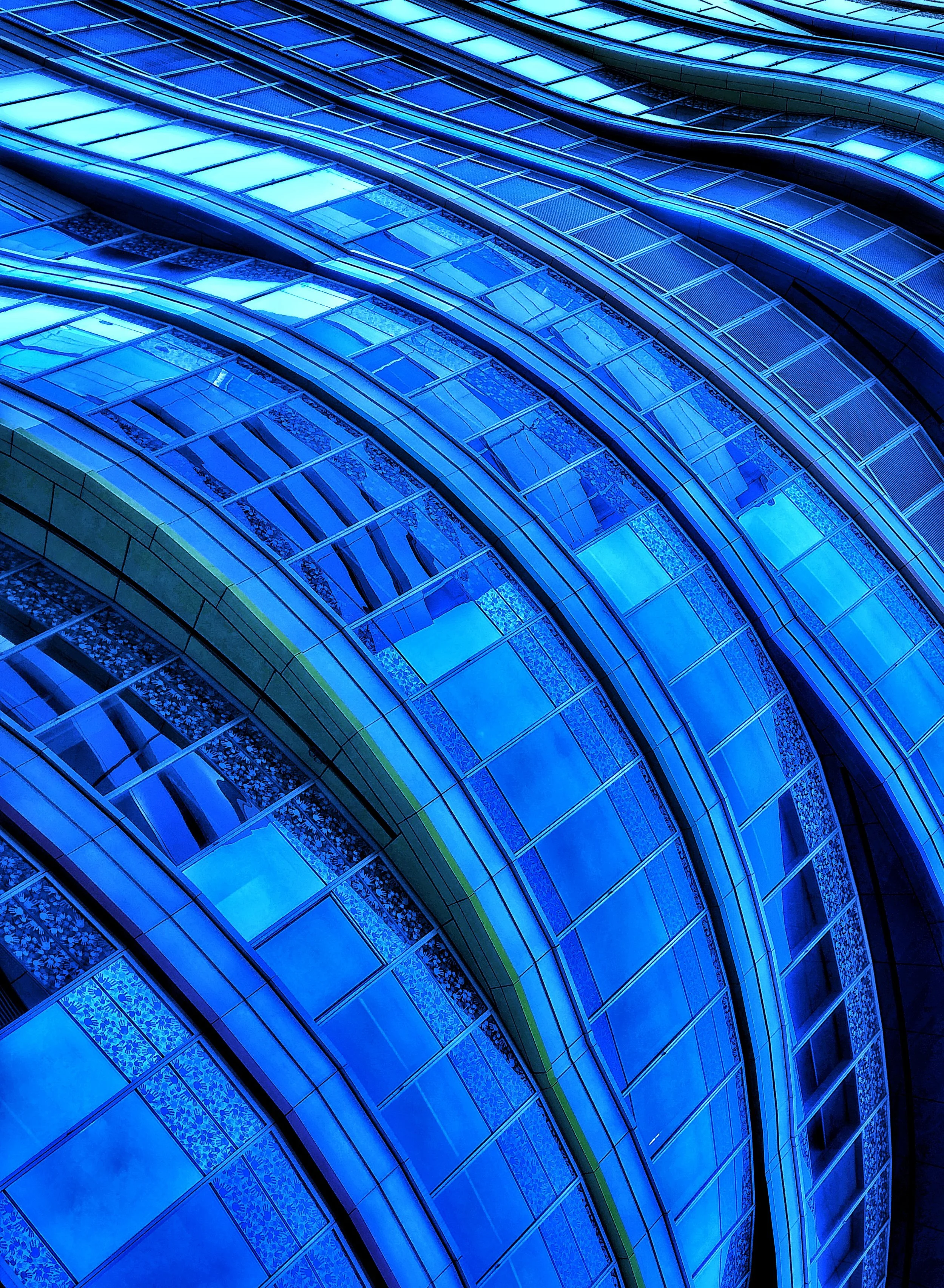 Abstract blue-tinted close-up of curved glass building facade with repeating window panels