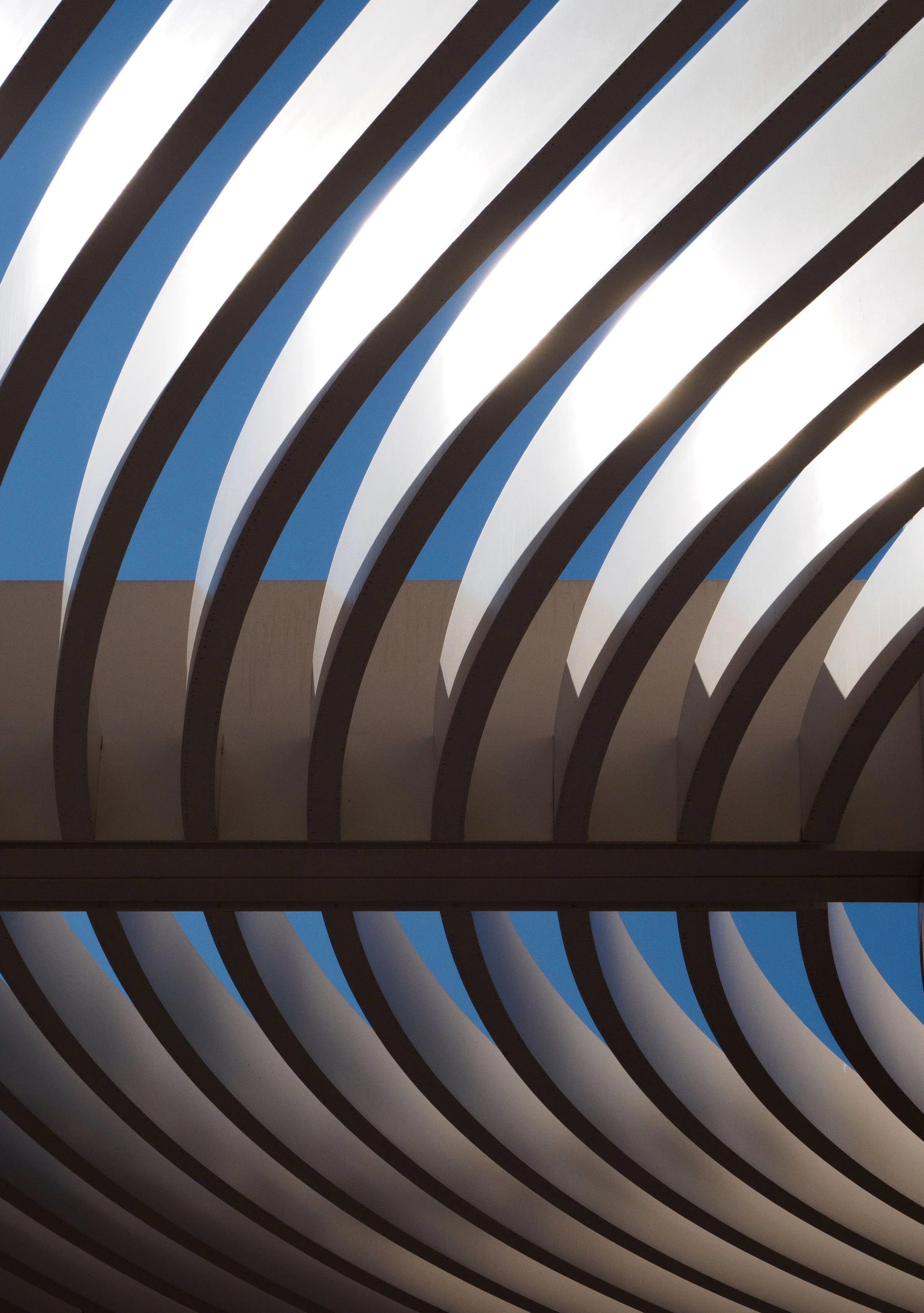 Abstract architectural view of repeating black and white diagonal beams against a blue sky