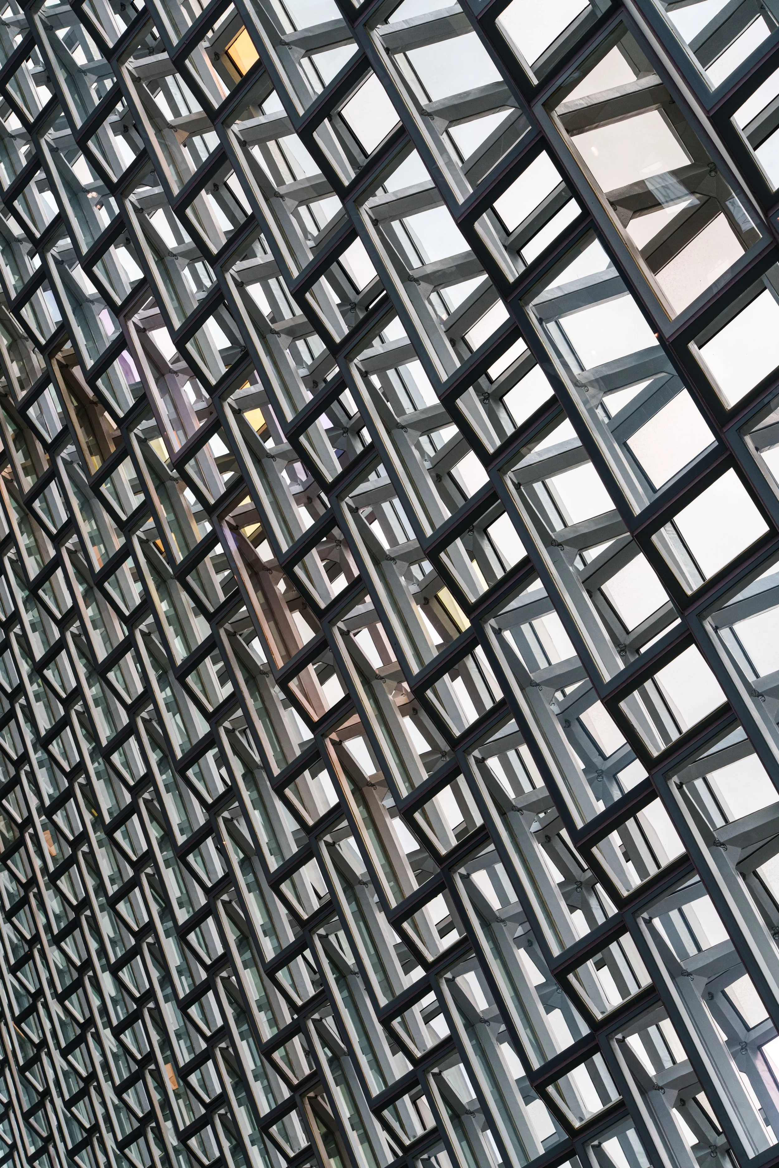 Abstract view of a modern glass-and-steel architectural facade with repeating diagonal rectangular frames.