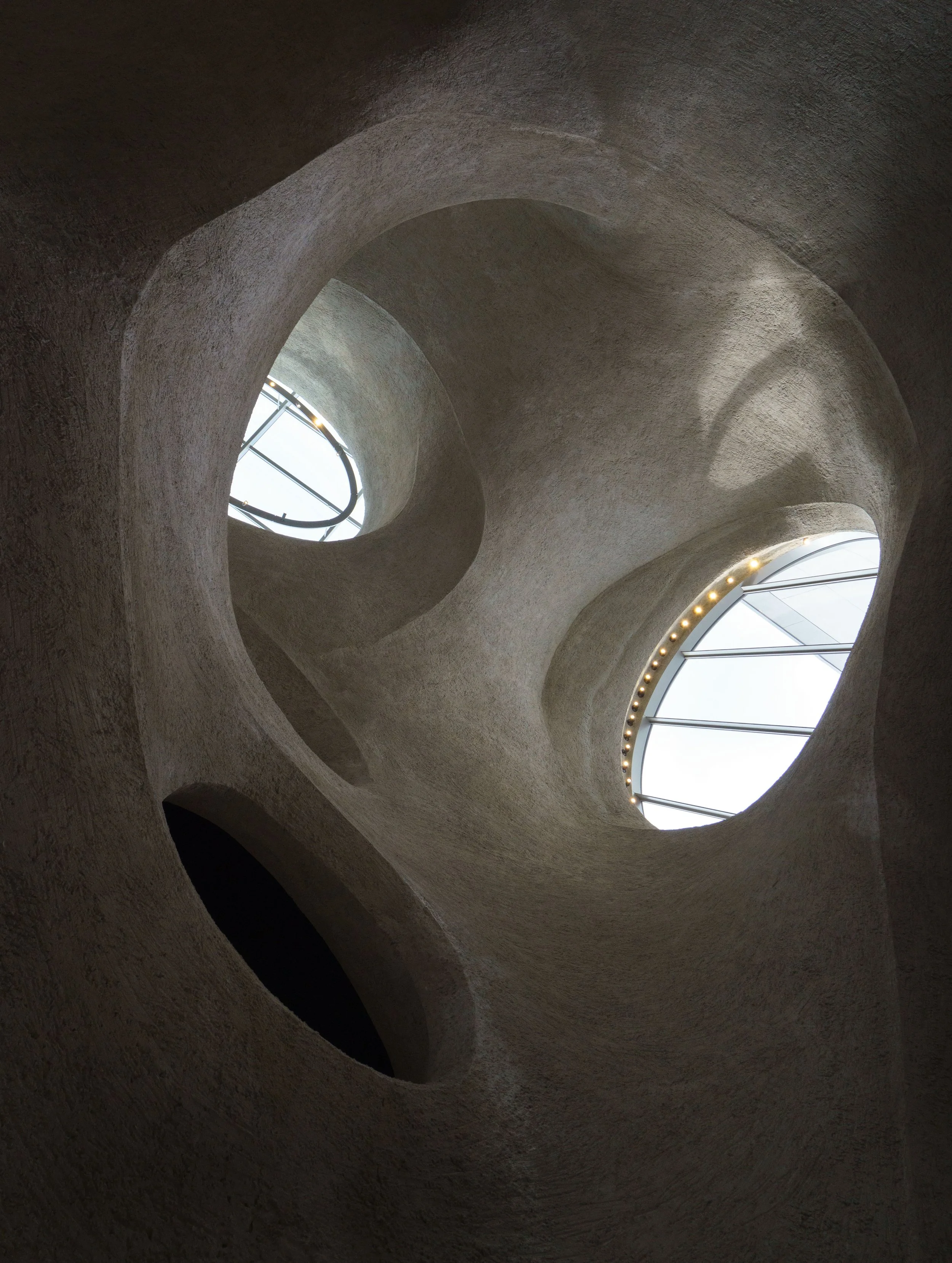 Interior of a sculptural concrete structure with sweeping arches and skylights