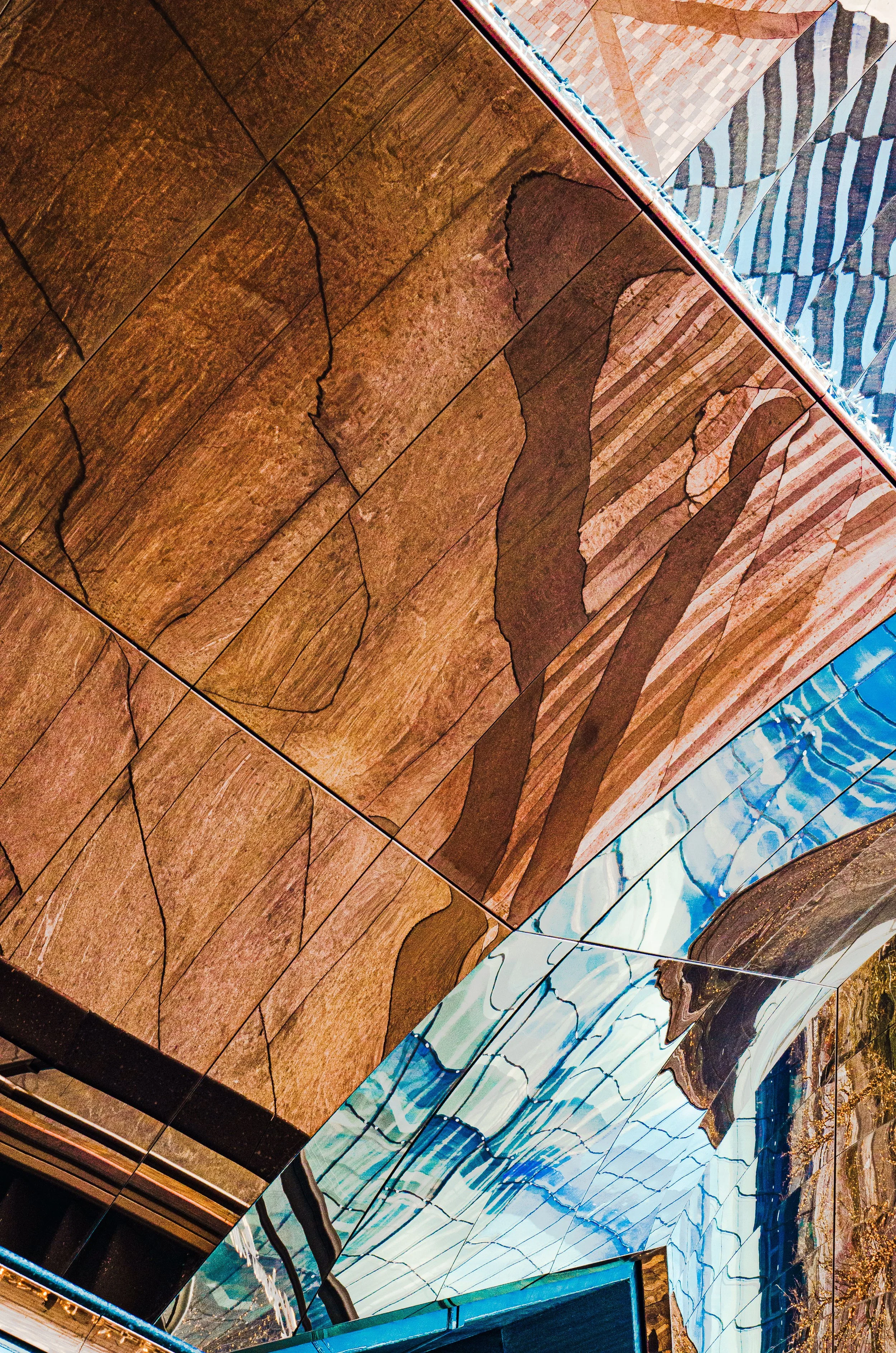 Close-up abstract stained-glass window with brown, white, blue, and turquoise geometric panels, dark lead lines, and colorful textured detailing