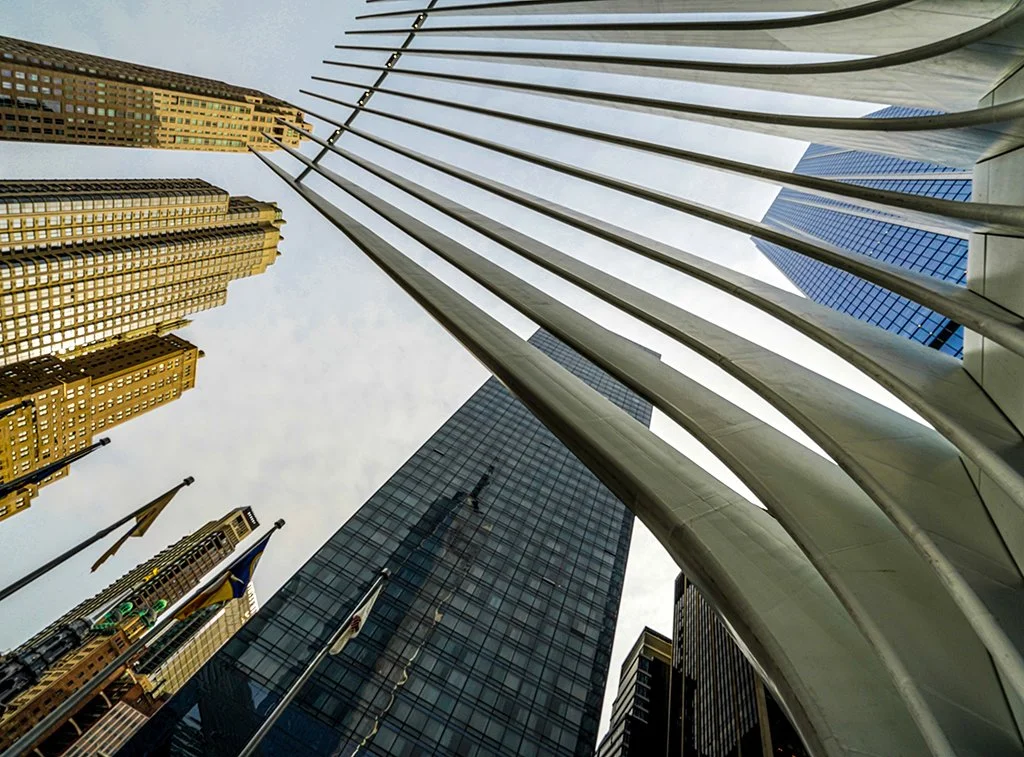 Upward view of skyscrapers and the sweeping steel arches of Chicago’s Wrigley Building plaza.