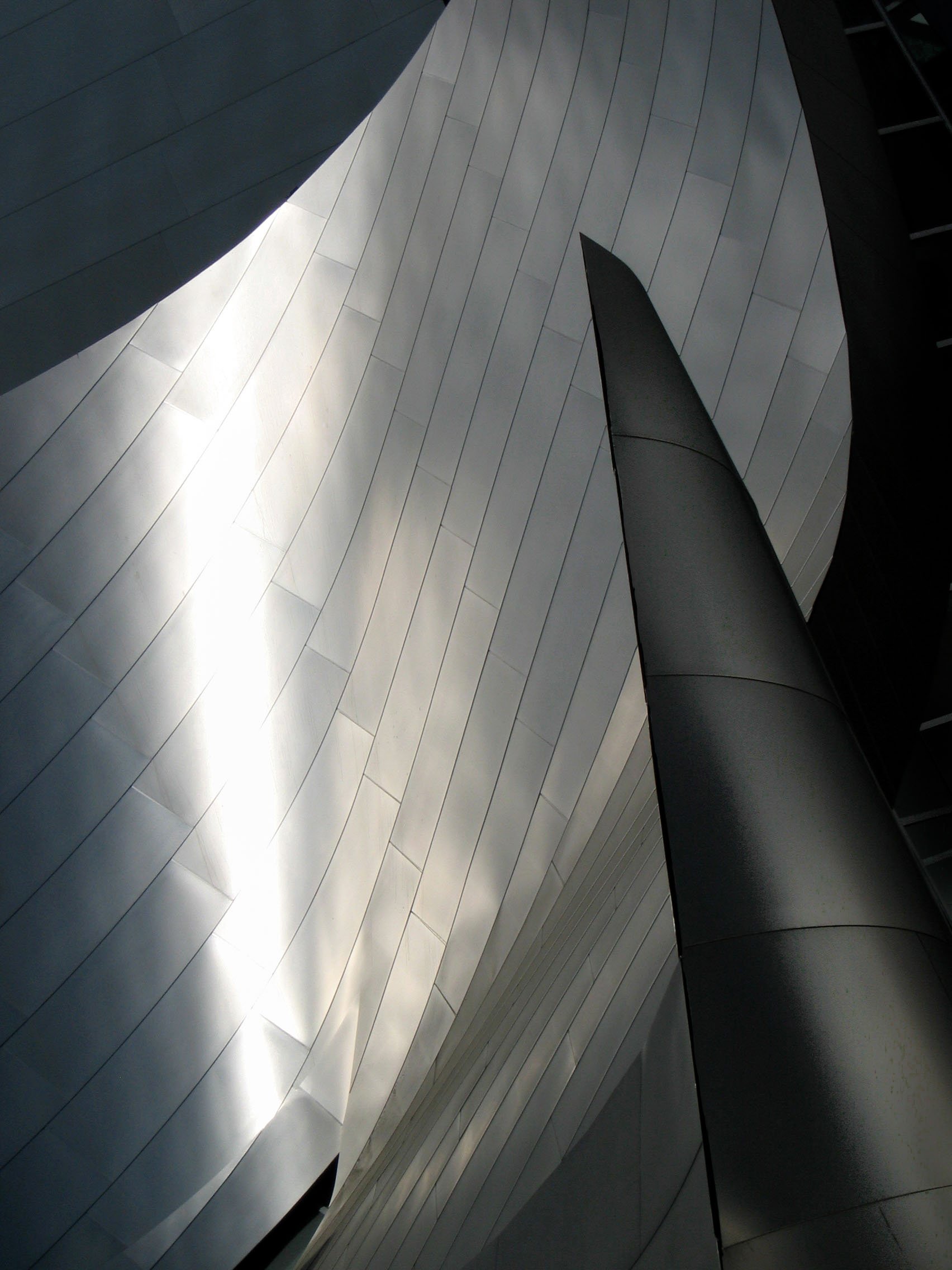 Abstract architectural view of curved metallic panels and geometric building surfaces
