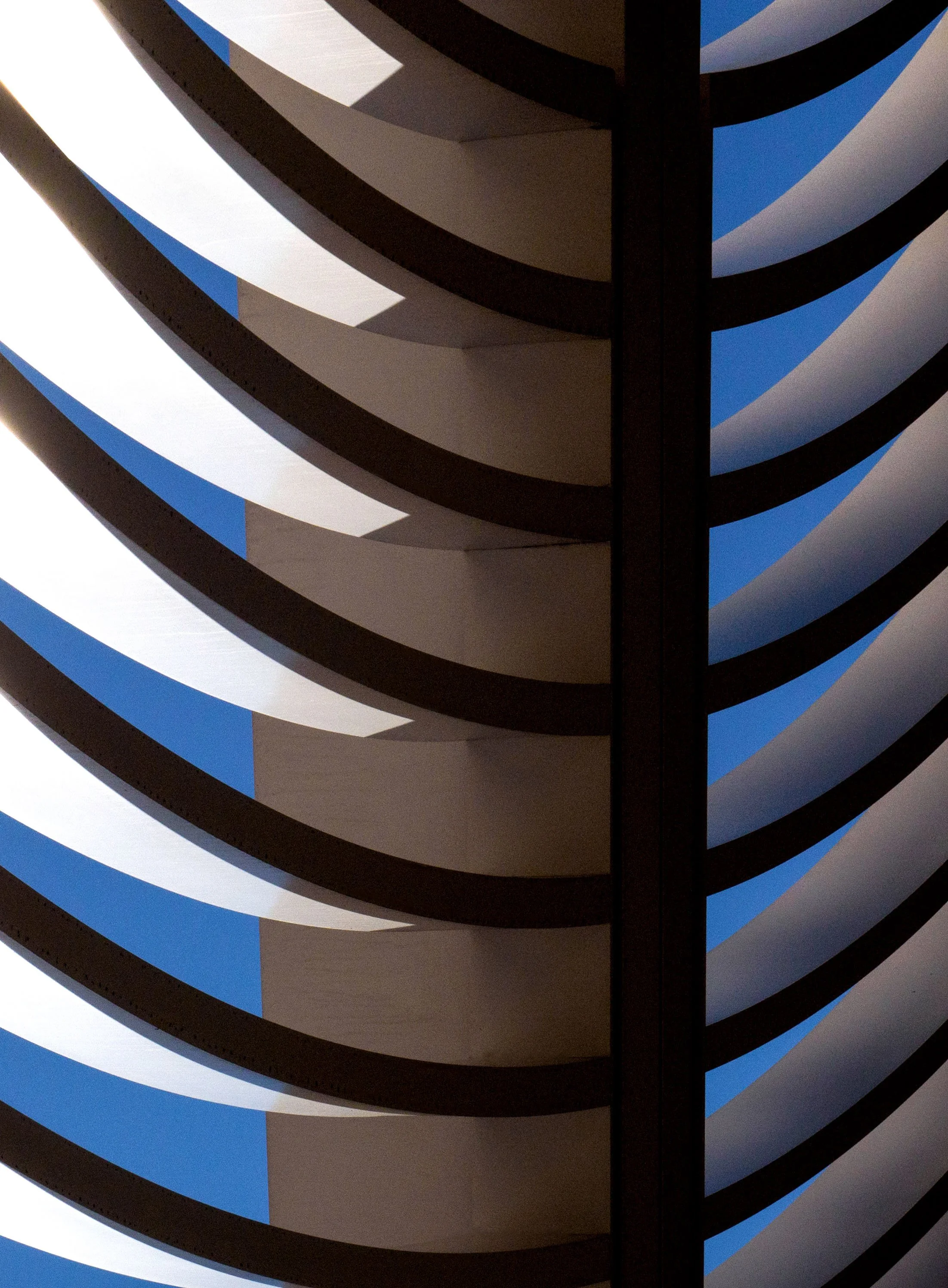 Abstract close-up of curved black, white, gray, and blue striped bands forming a geometric pattern.