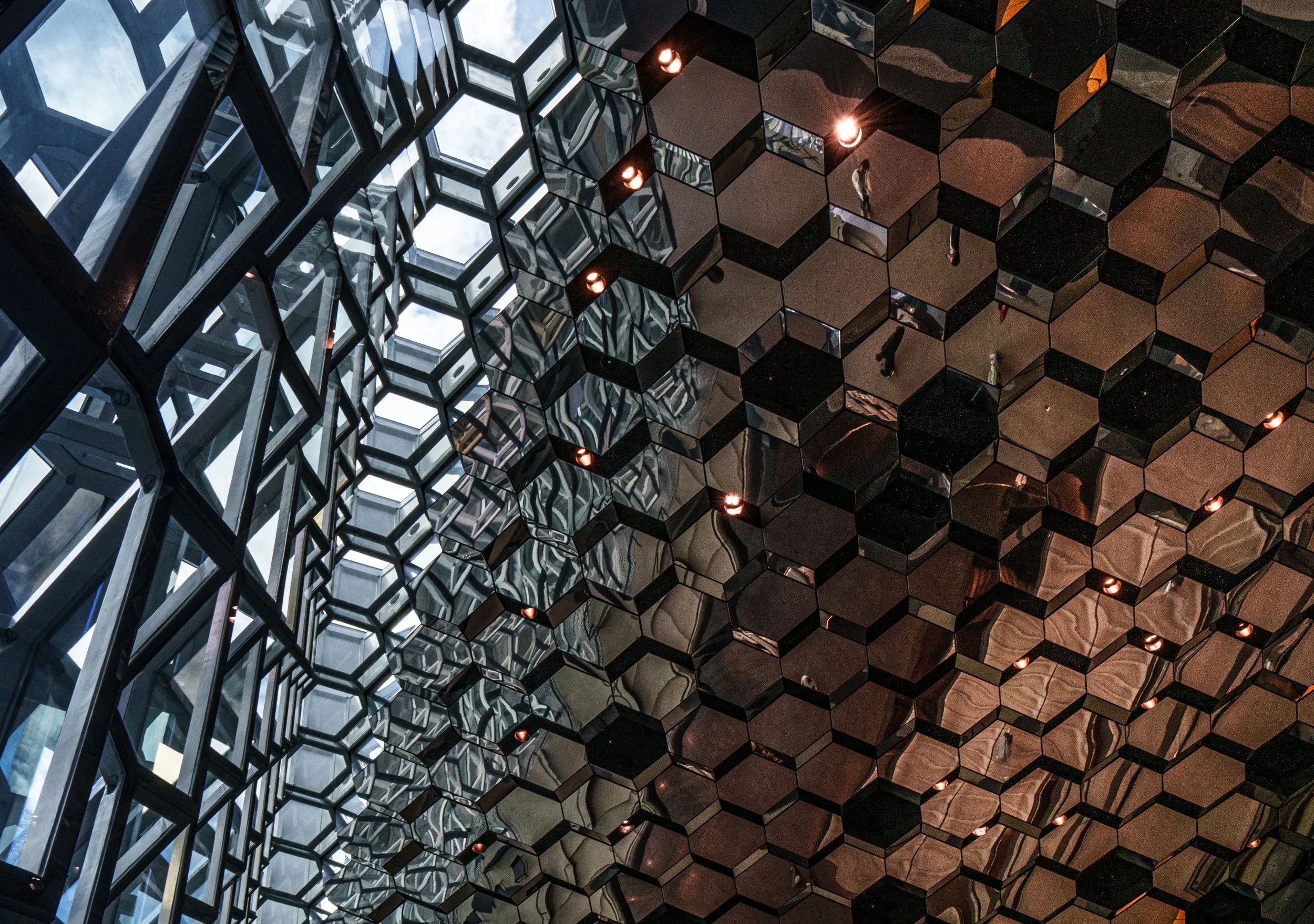 Reflective mirrored ceiling with geometric hexagonal panels, skylights, and warm spotlights