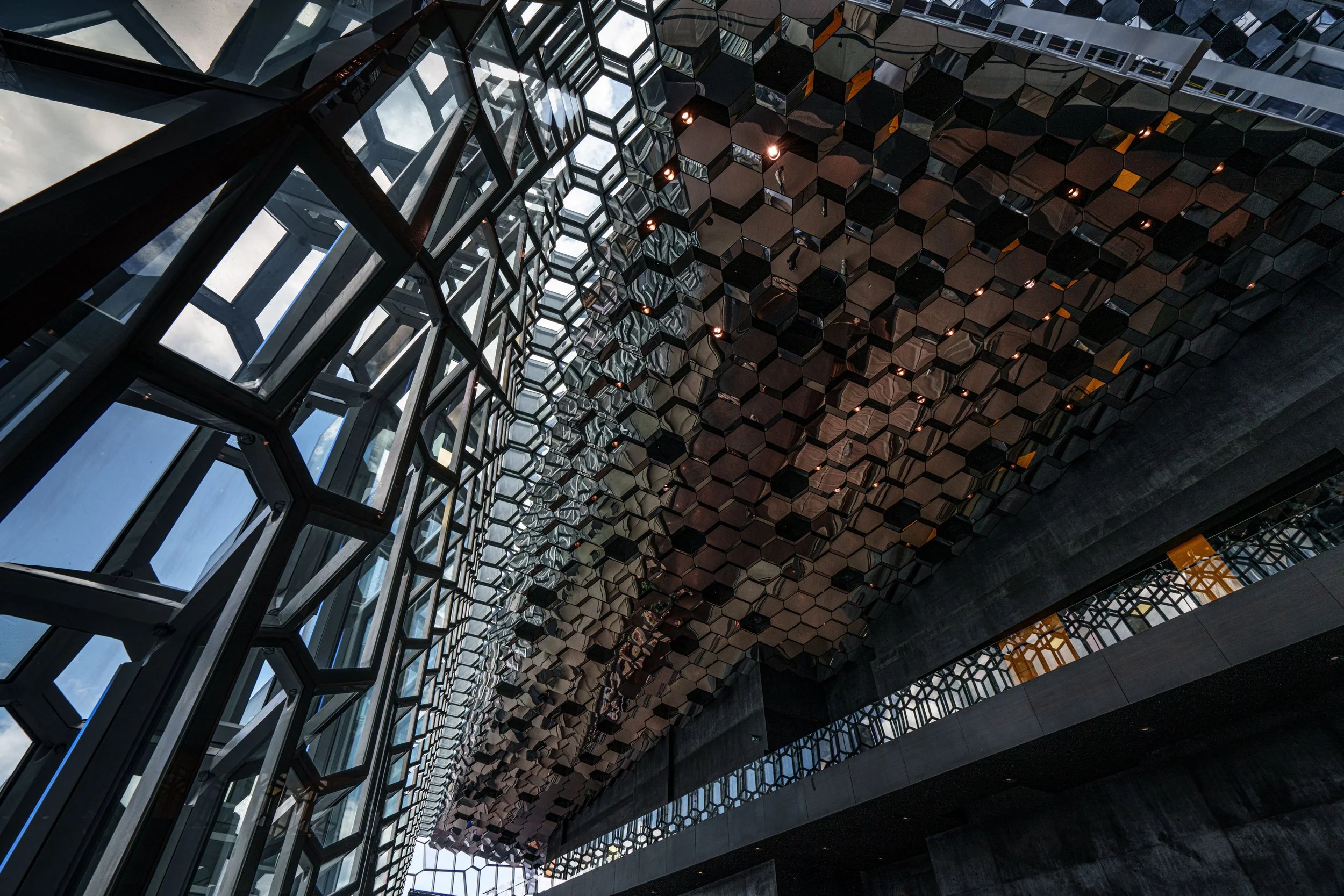 Contemporary atrium with geometric glass windows and a reflective honeycomb-patterned ceiling