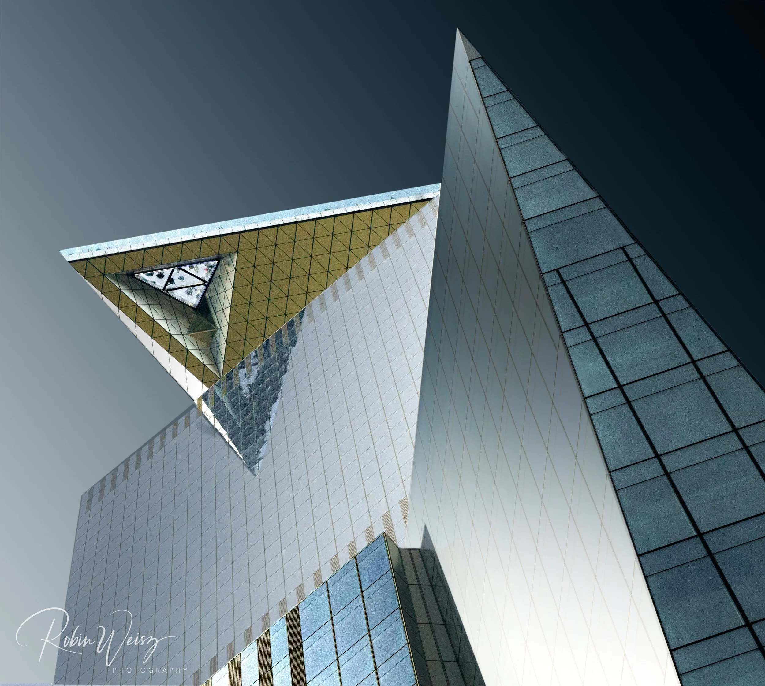 Abstract upward view of modern geometric skyscraper facades against a dark blue sky