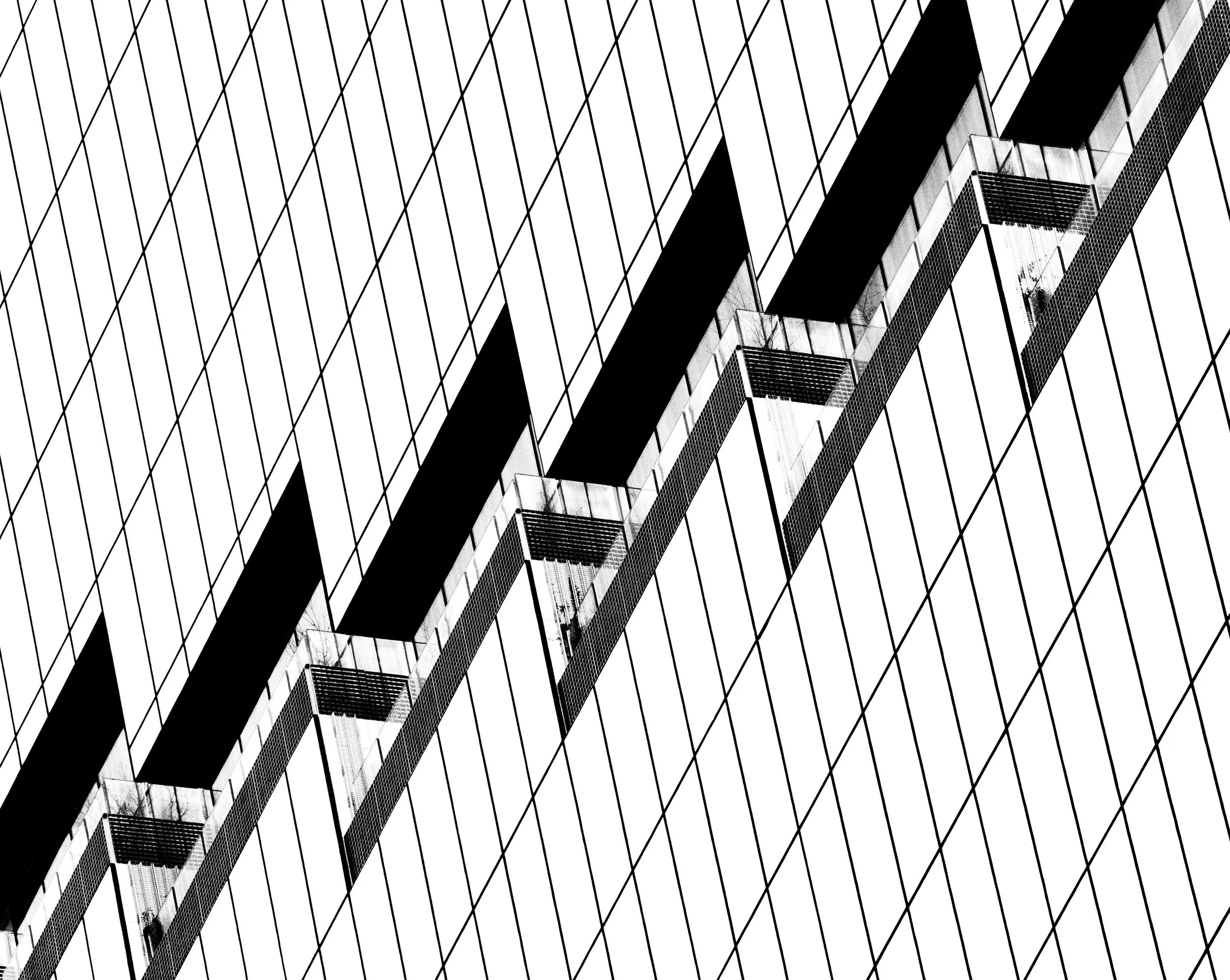 High-contrast black-and-white abstract view of a modern building facade with geometric lines and repeating balconies