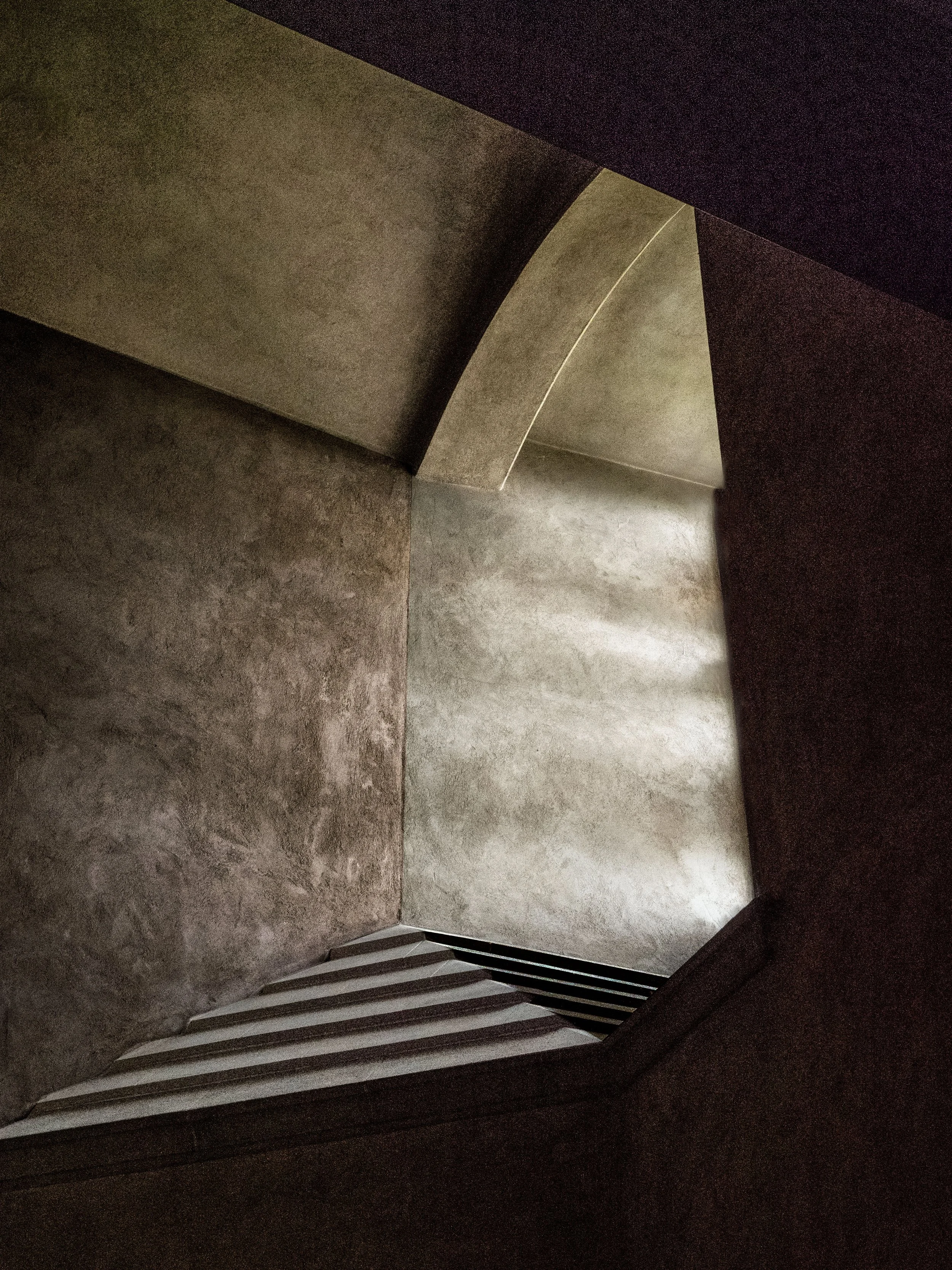 Abstract low-angle view of geometric concrete architecture with angular walls, stairs, and dramatic shadows