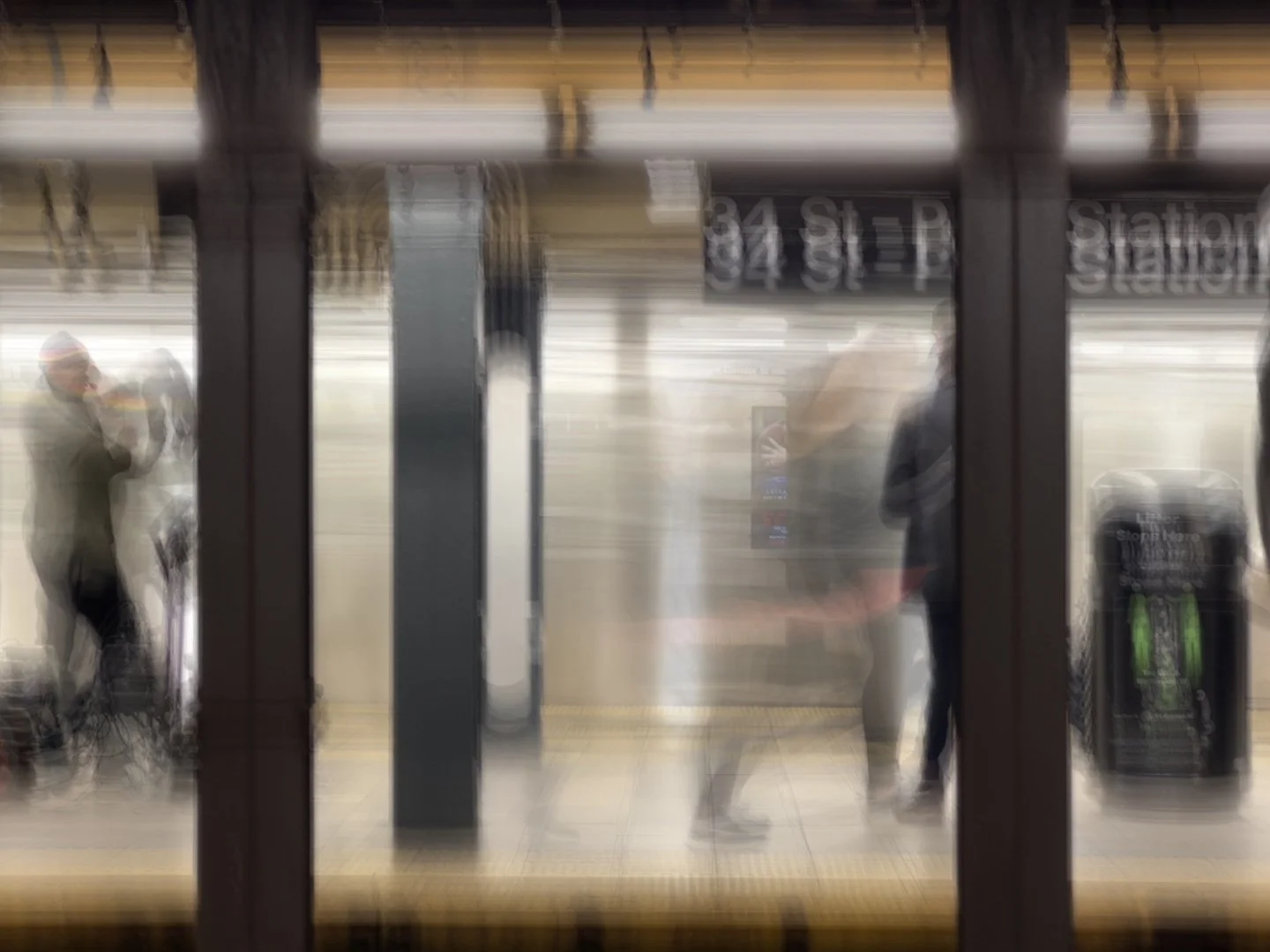 Motion-blurred passengers on a subway platform beneath a 34 St–Penn Station sign