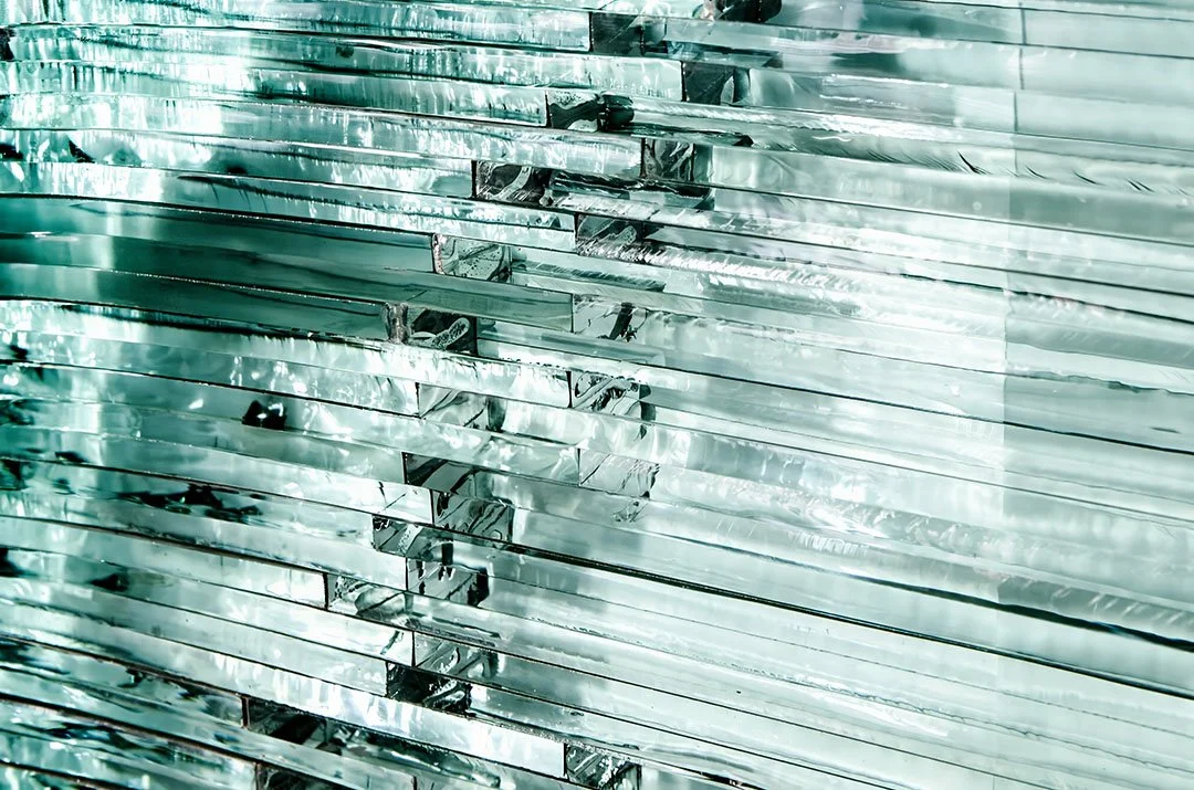 Close-up of layered translucent ice-like crystal slabs with reflective horizontal striations