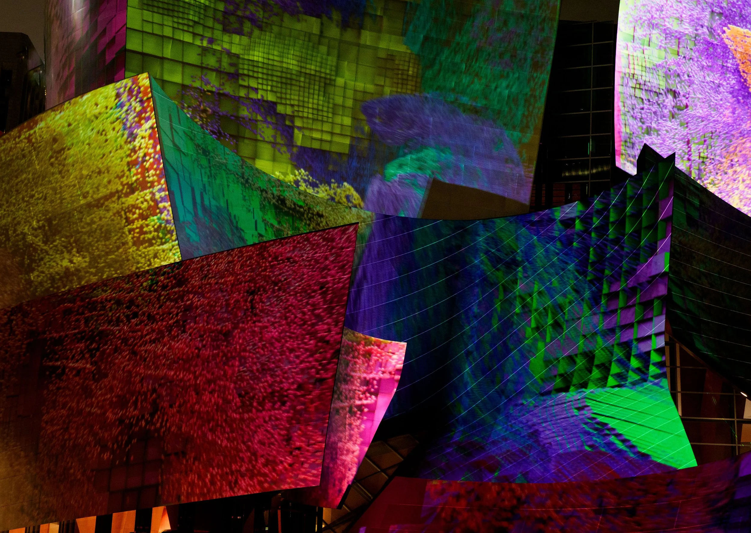 Abstract immersive light installation with colorful projections of flowing textures on angular screens inside a dark building