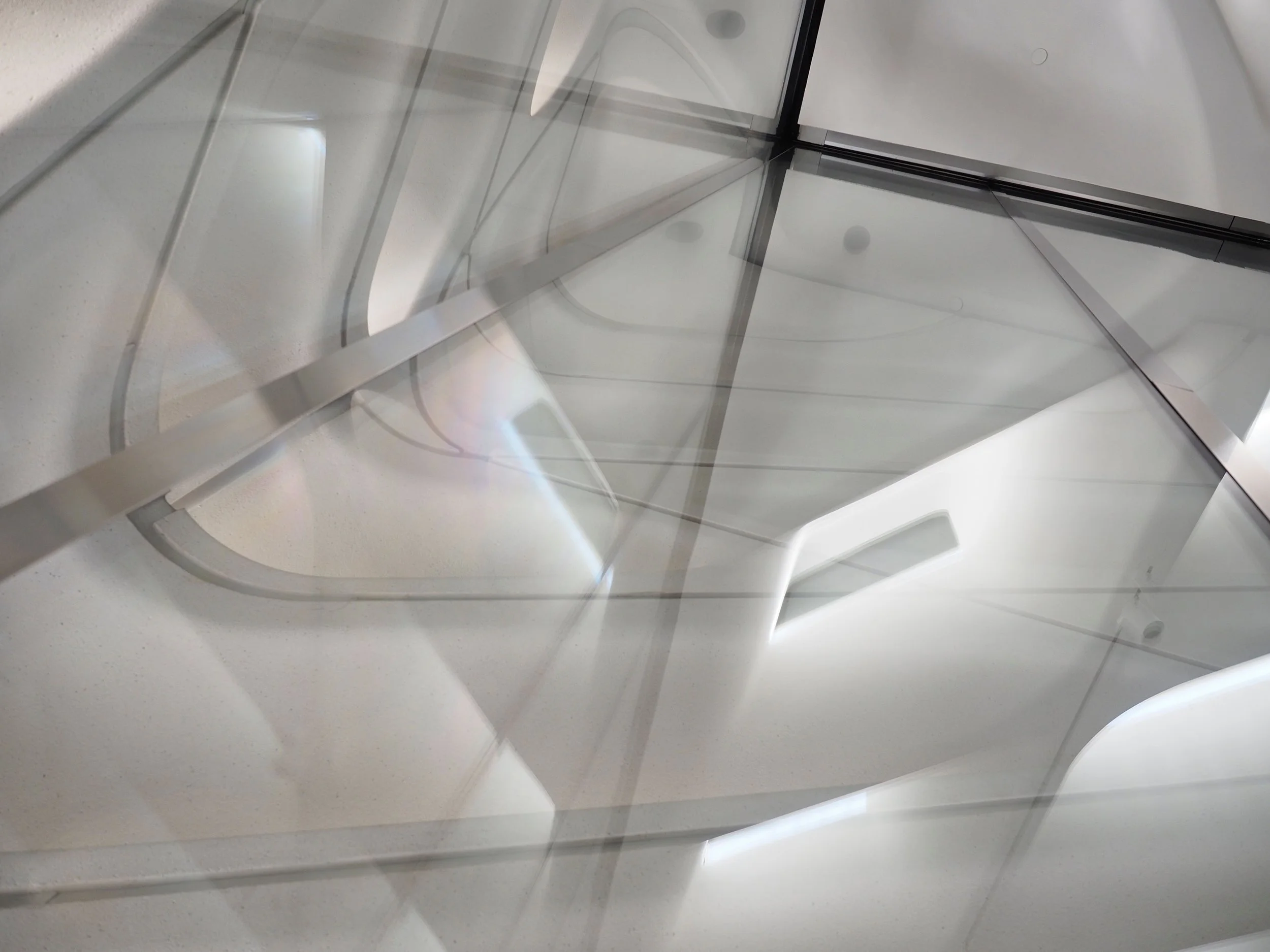 Abstract close-up of white geometric architectural panels and intersecting glass surfaces