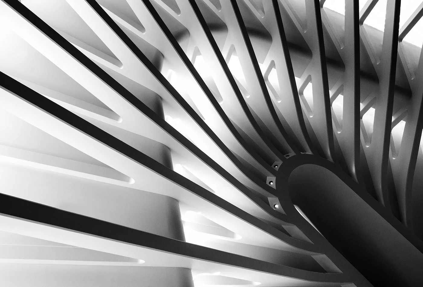 Abstract black-and-white close-up of a modern spiral staircase with repeating architectural steps and railings