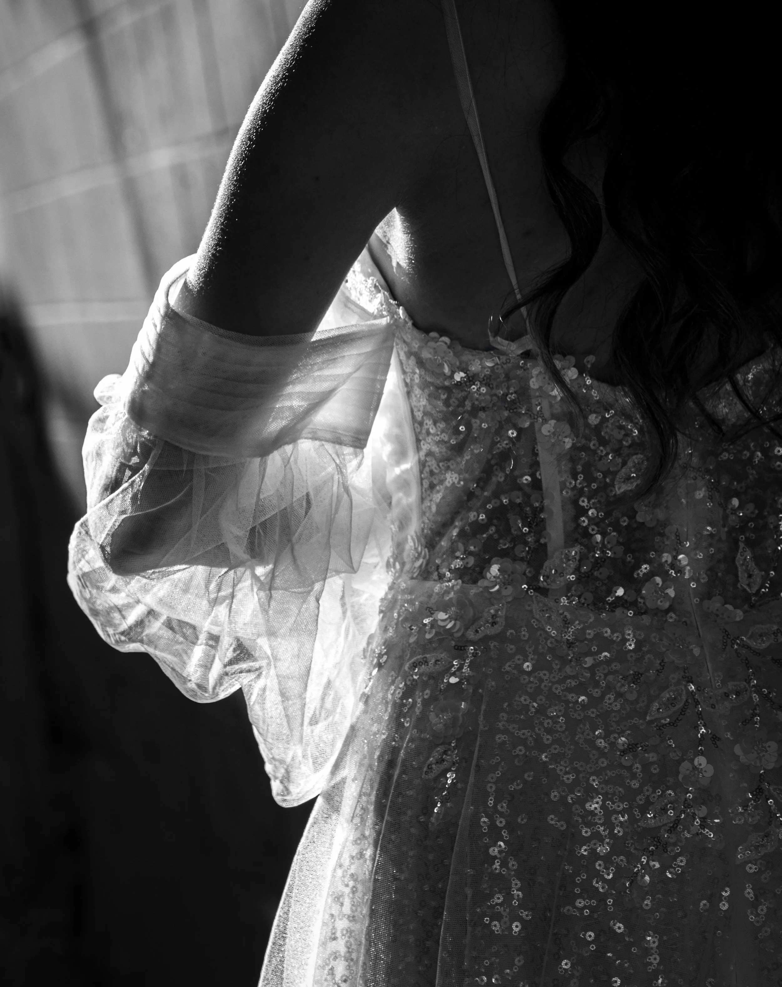 Black-and-white close-up of a person in a sequined dress with sheer ruffled sleeves