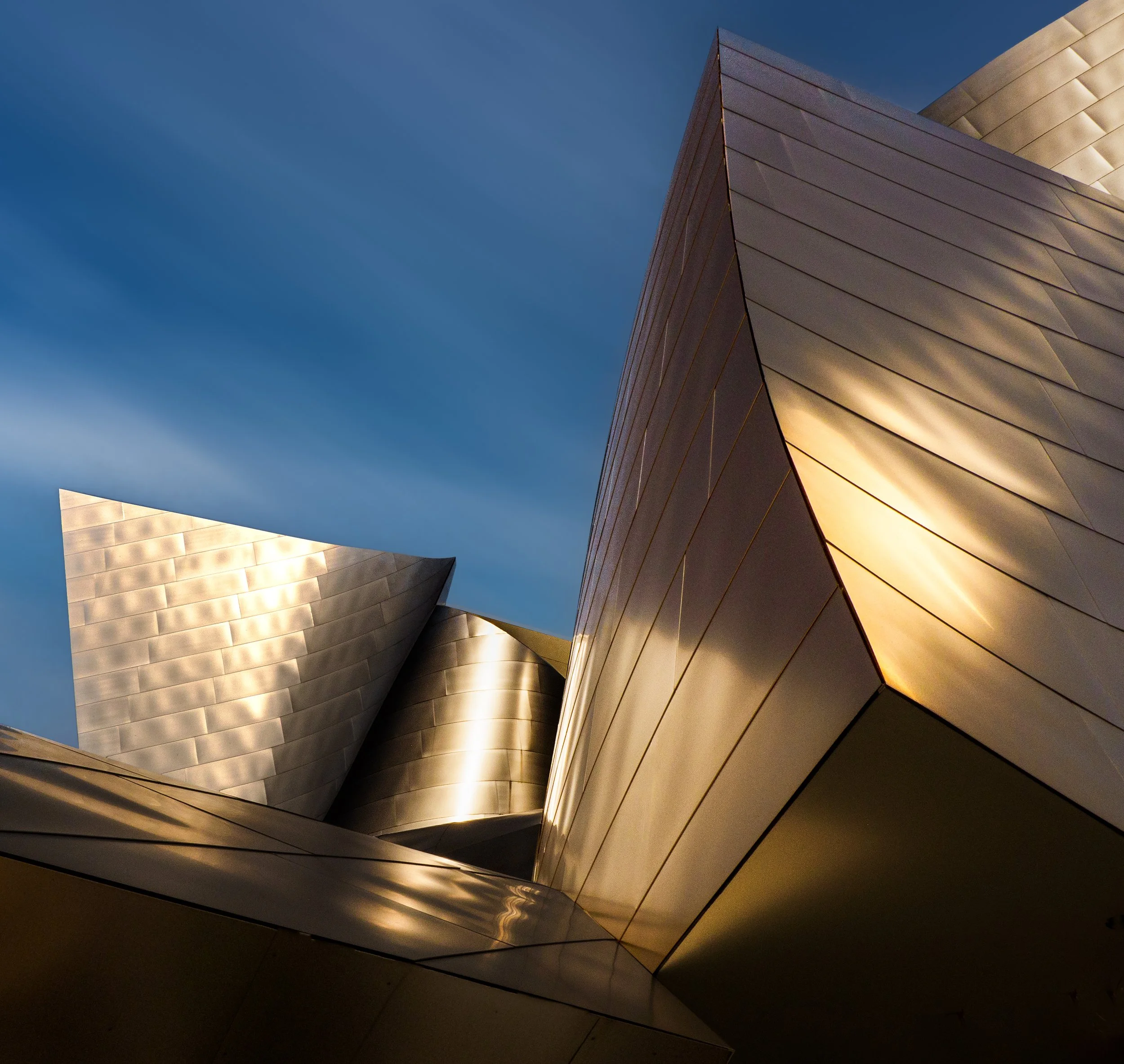 Upward view of the Walt Disney Concert Hall’s curving stainless steel facade against a blue sky