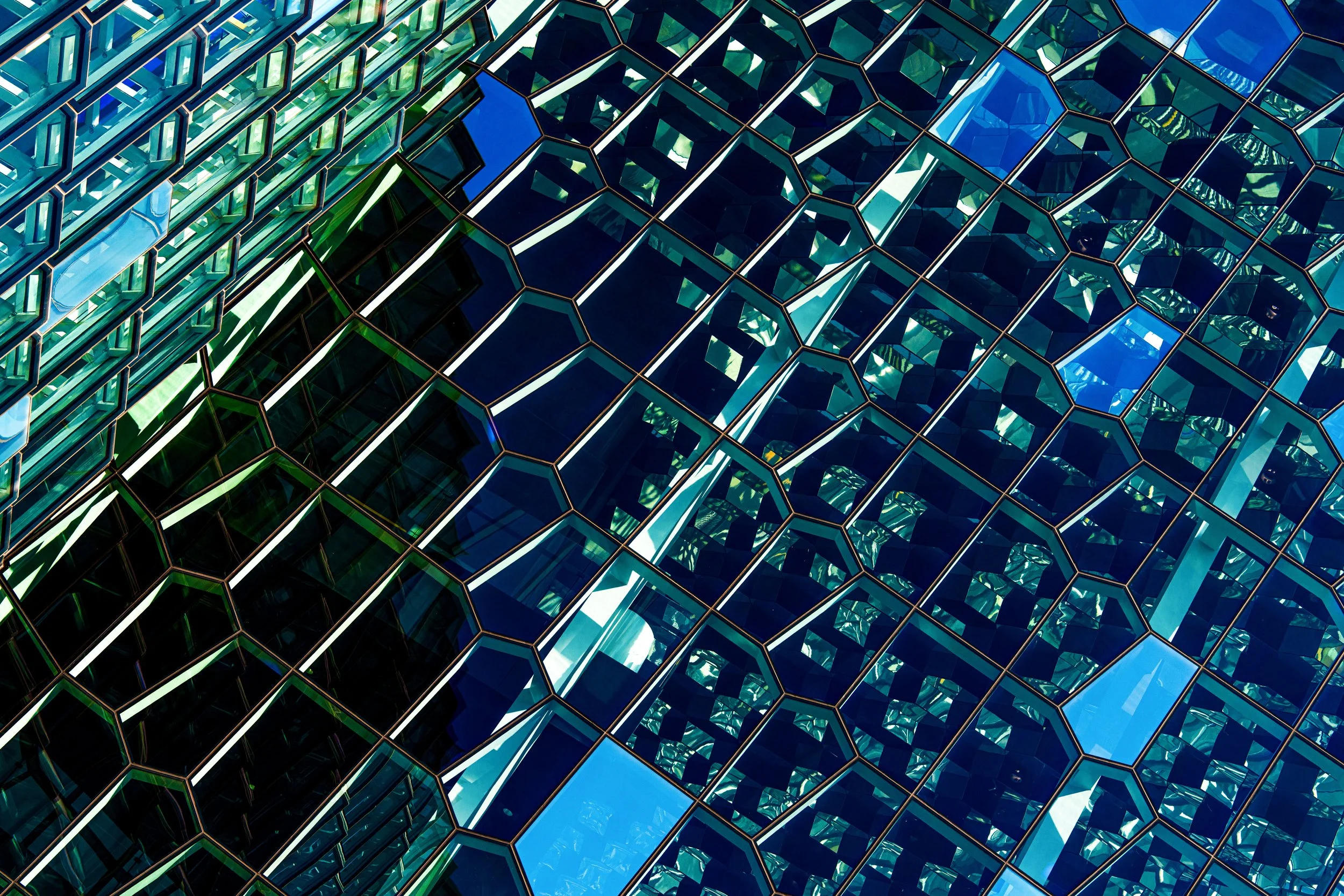 Abstract geometric pattern of reflective blue and teal glass panels
