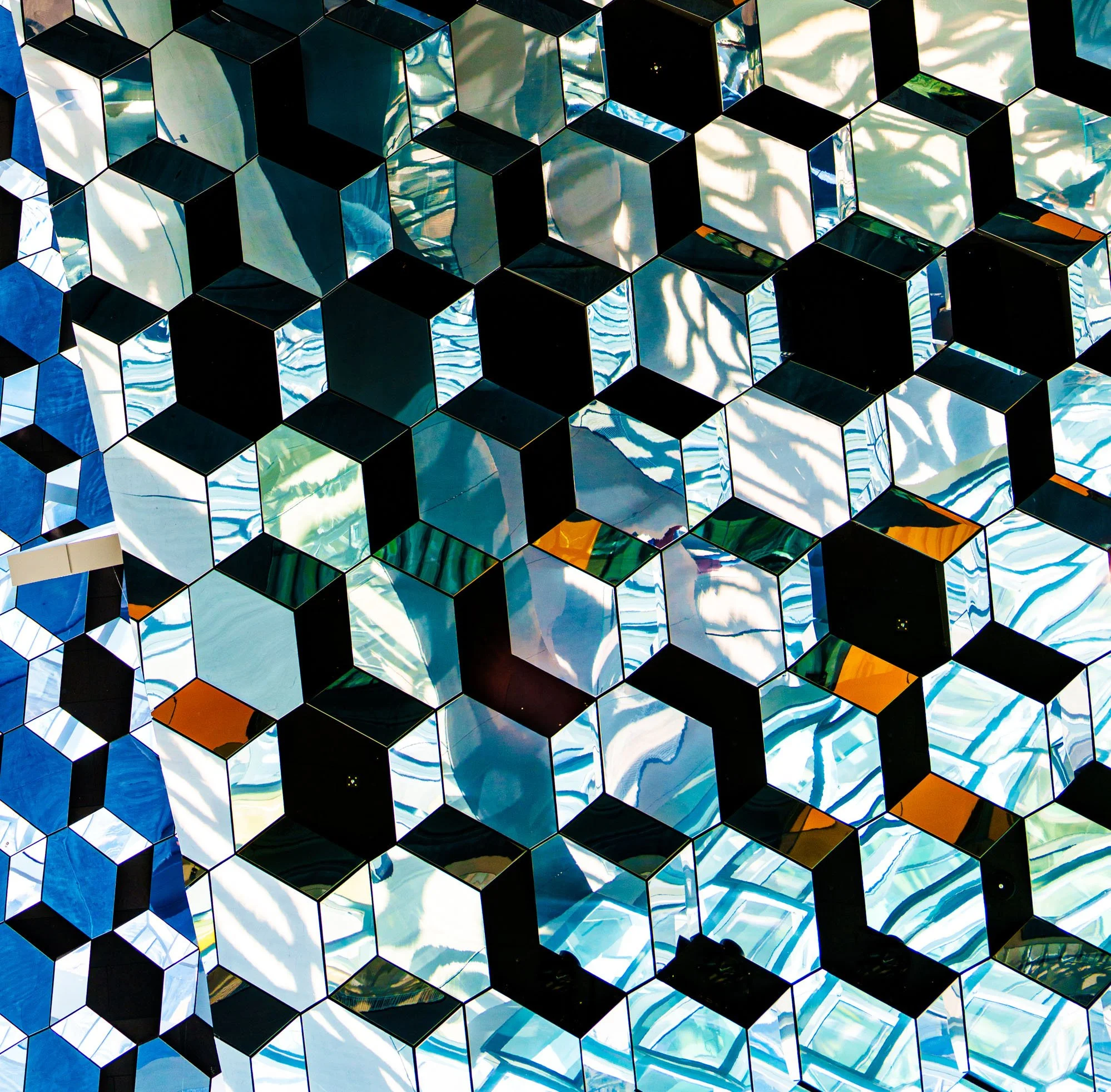 Abstract geometric pattern of reflective blue, white, black, and orange cubes