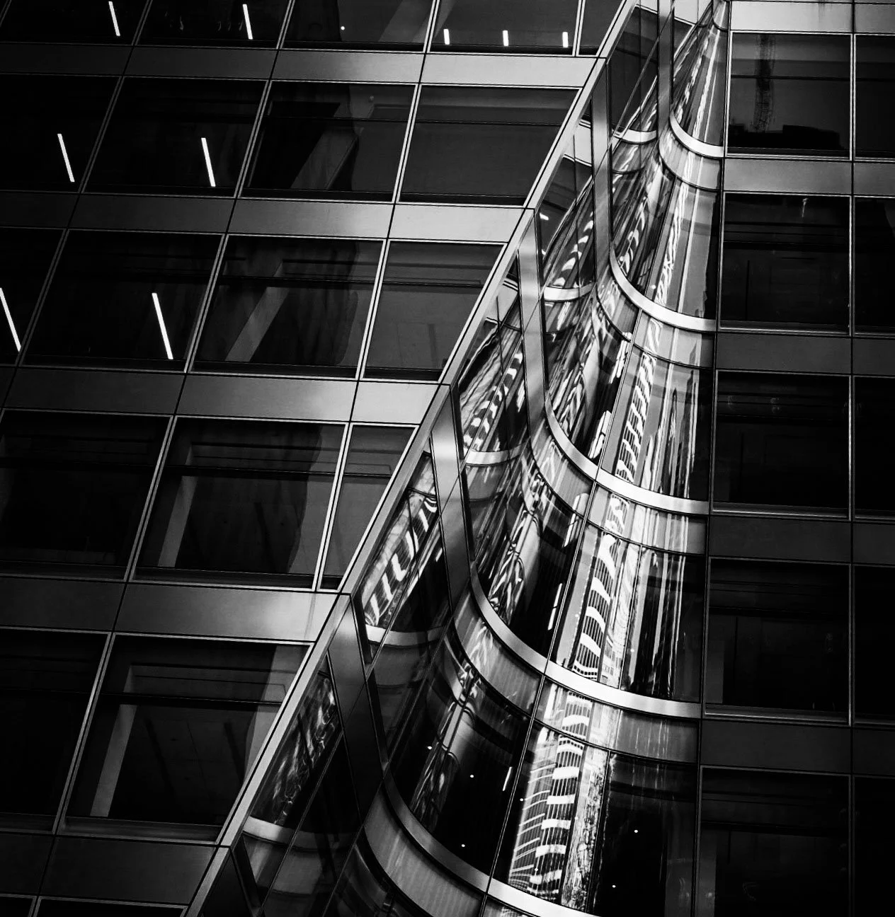 Black-and-white abstract view of reflective glass skyscraper facades with geometric windows and curved architectural reflections