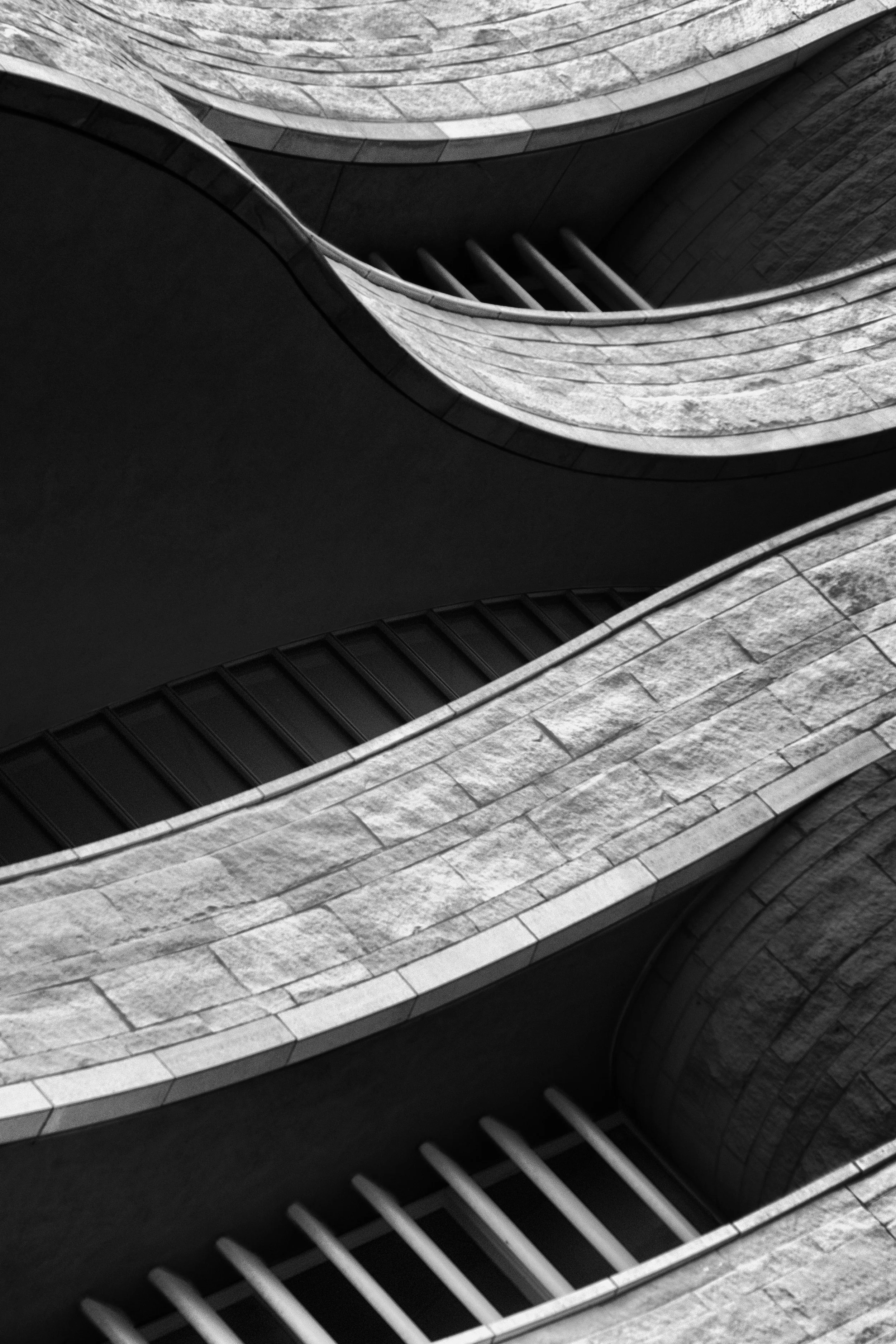 Black-and-white abstract architectural view of curved stone balconies and railings